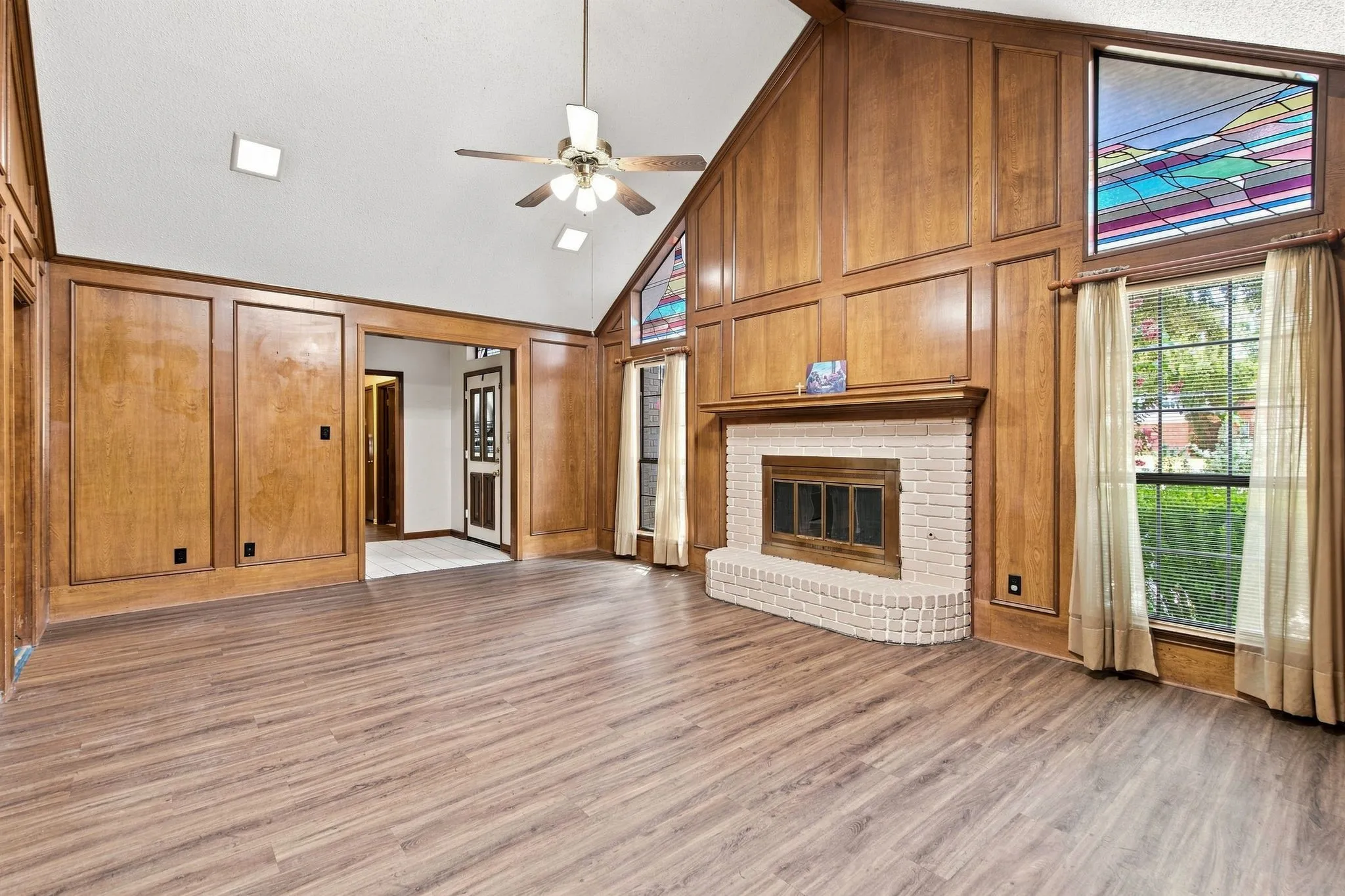 Vinyl plank flooring, vaulted ceiling, and wood-paneled walls