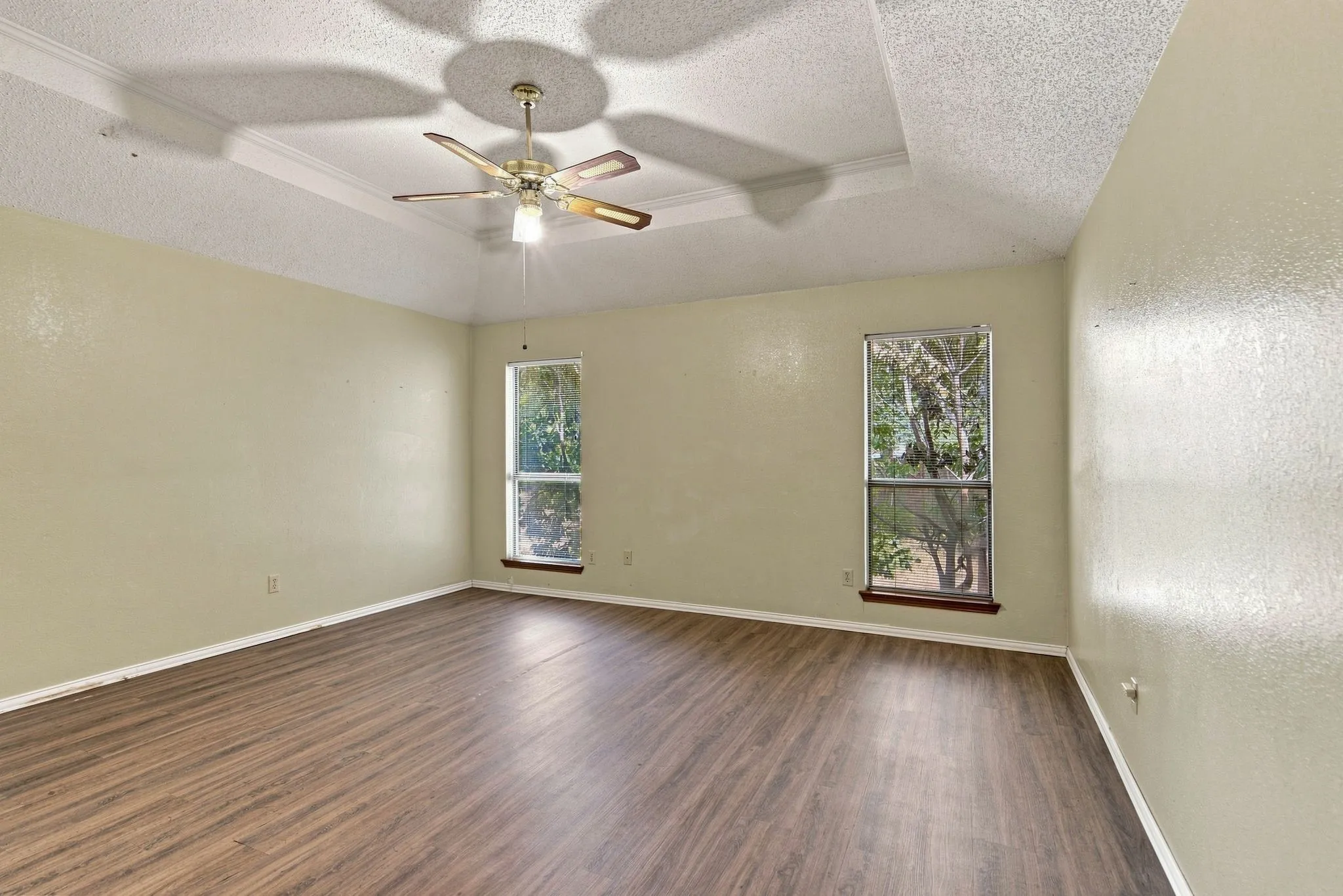 Vinyl Plank flooring with a tray ceiling and a ceiling fan