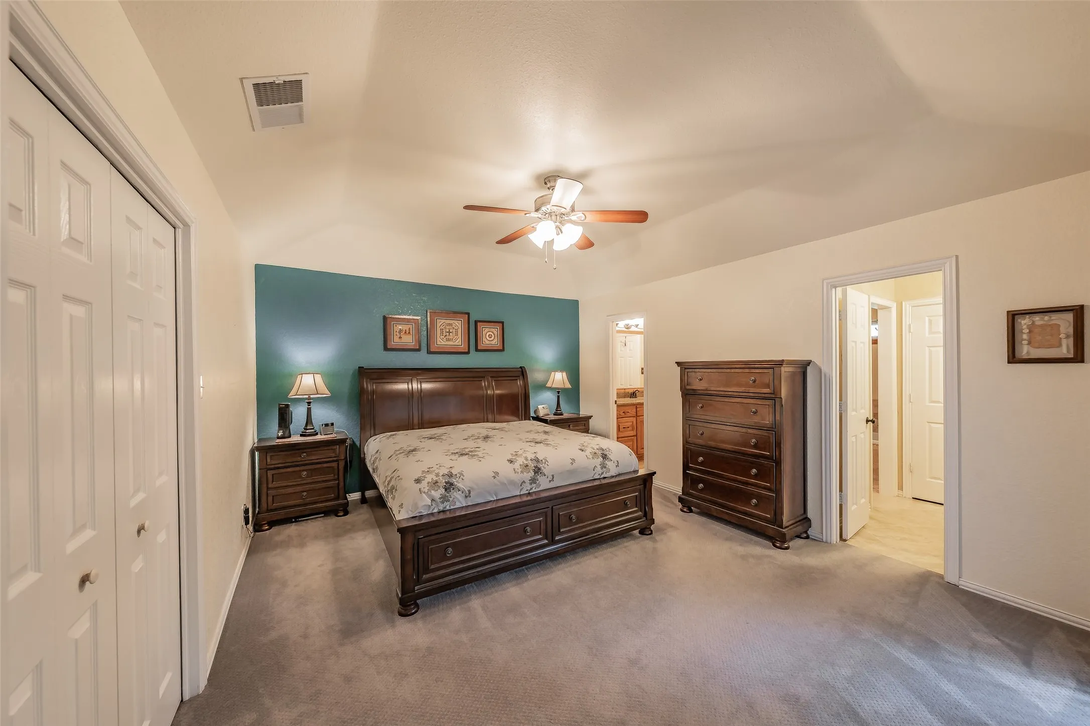Vaulted ceiling with ceiling fan, bifold closet doors, and neutral wall paint
