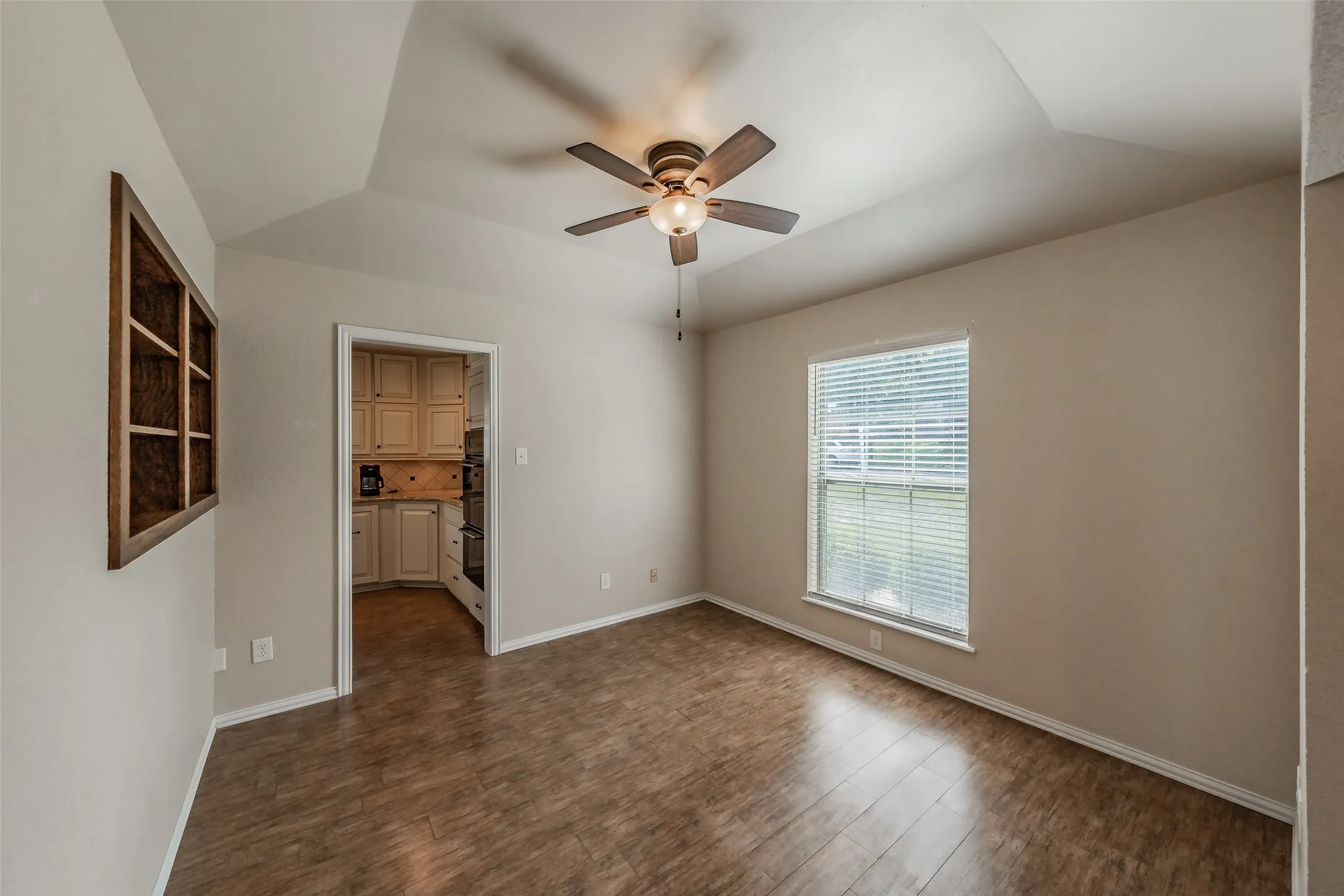 Vaulted ceiling with a ceiling fan, and tile floors that look like wood.