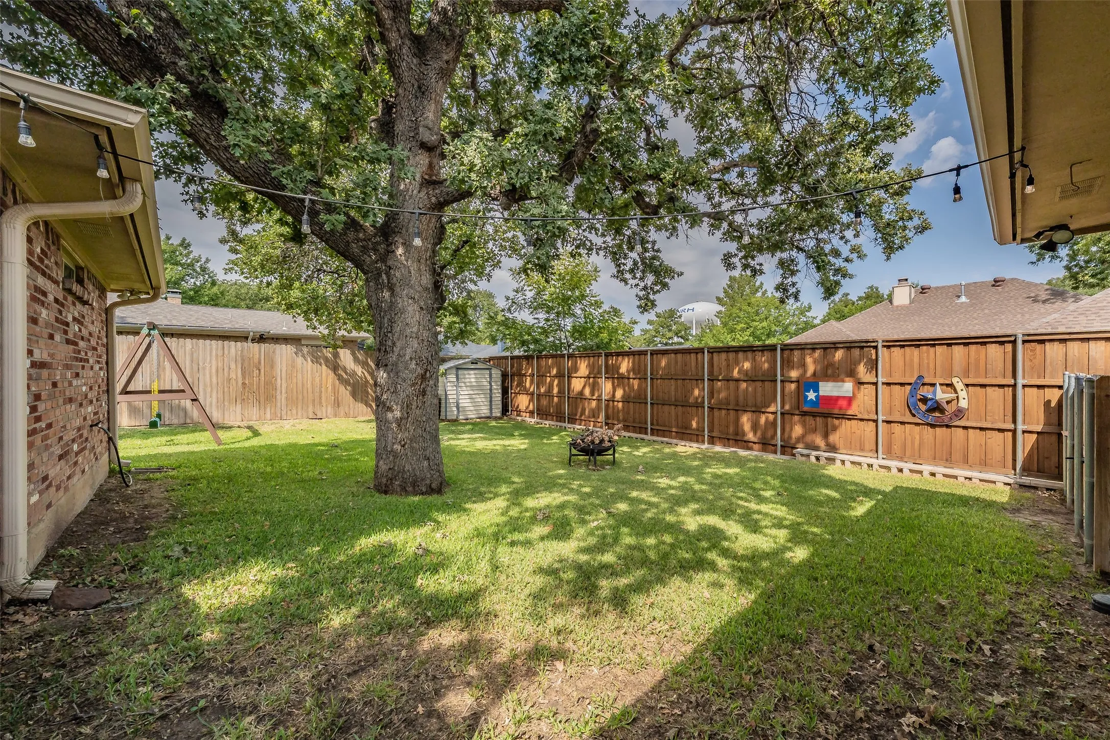 Expansive backyard featuring a mature tree, manicured lawn, and privacy fencing