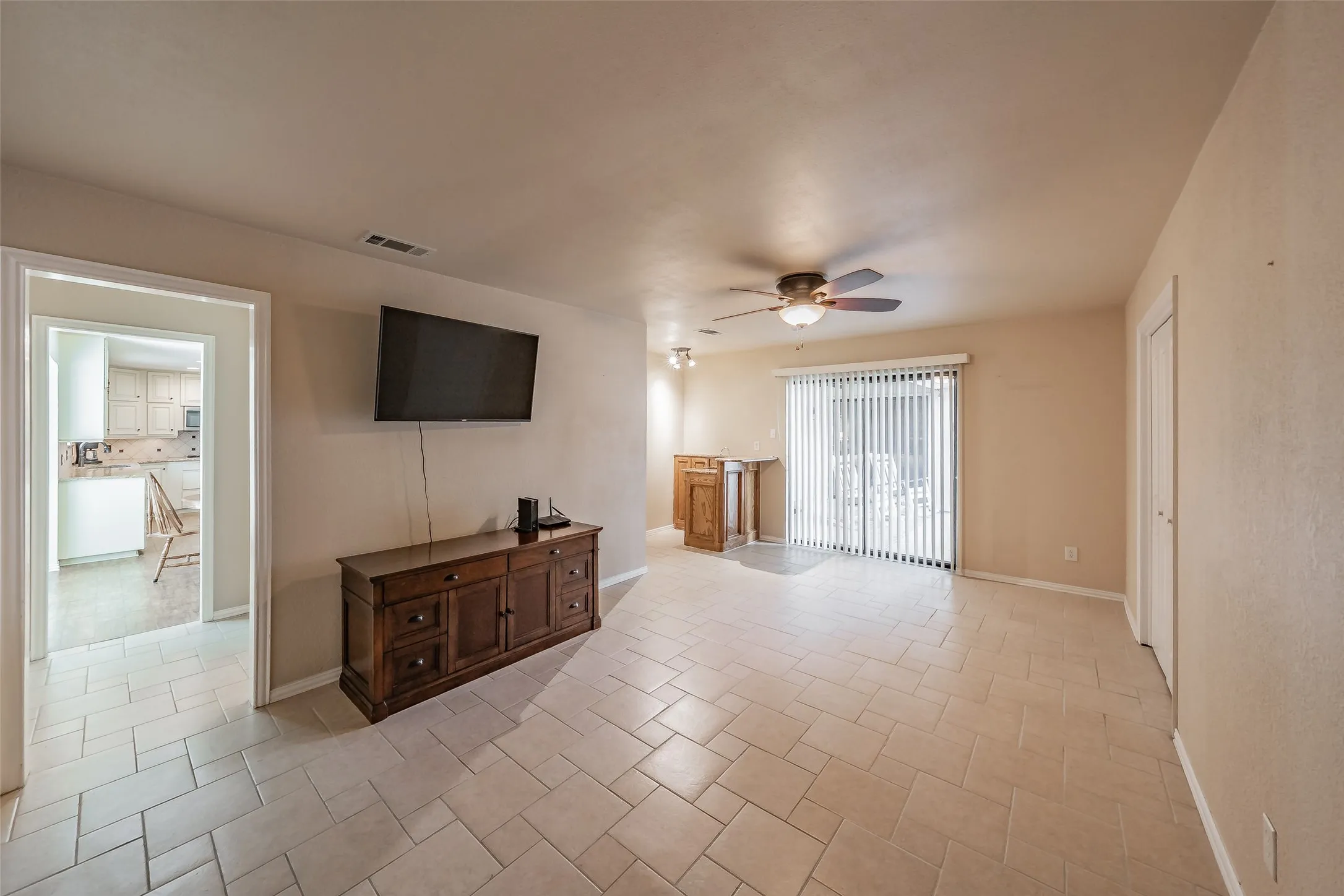 Neutral-toned tile flooring, recessed lighting, ceiling fan, and sliding glass door with vertical blinds