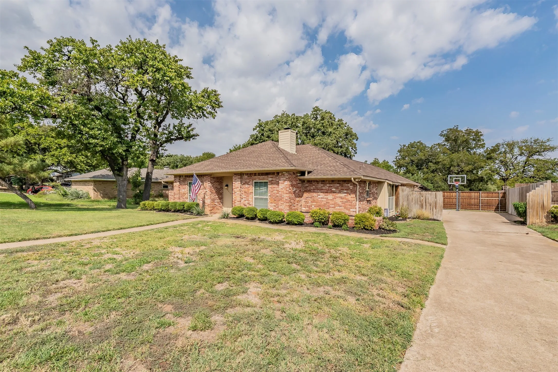 Brick exterior featuring a gabled roof and a drive