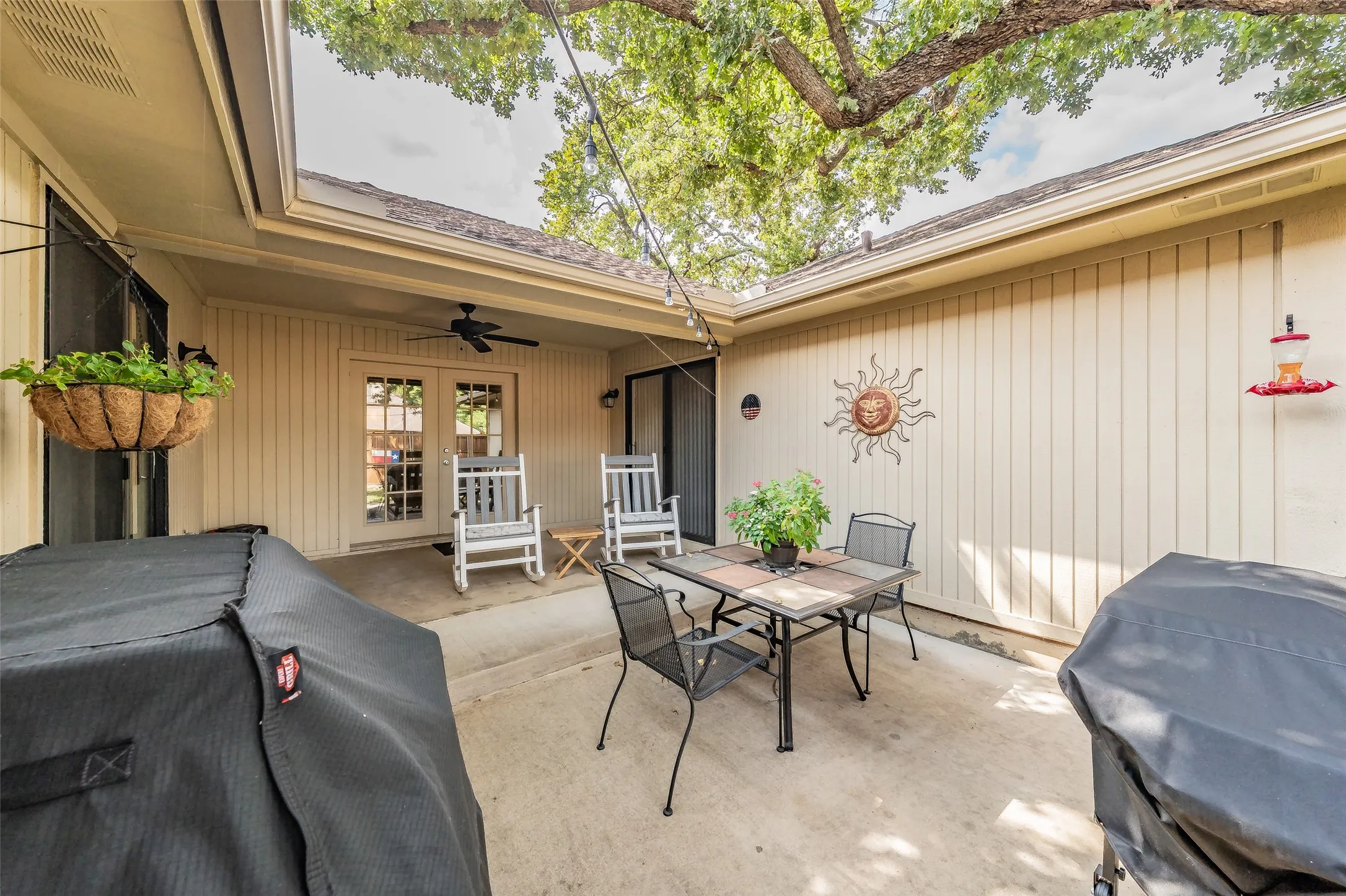 Concrete patio with a covered outdoor area featuring an outdoor ceiling fan, string lighting, and French doors