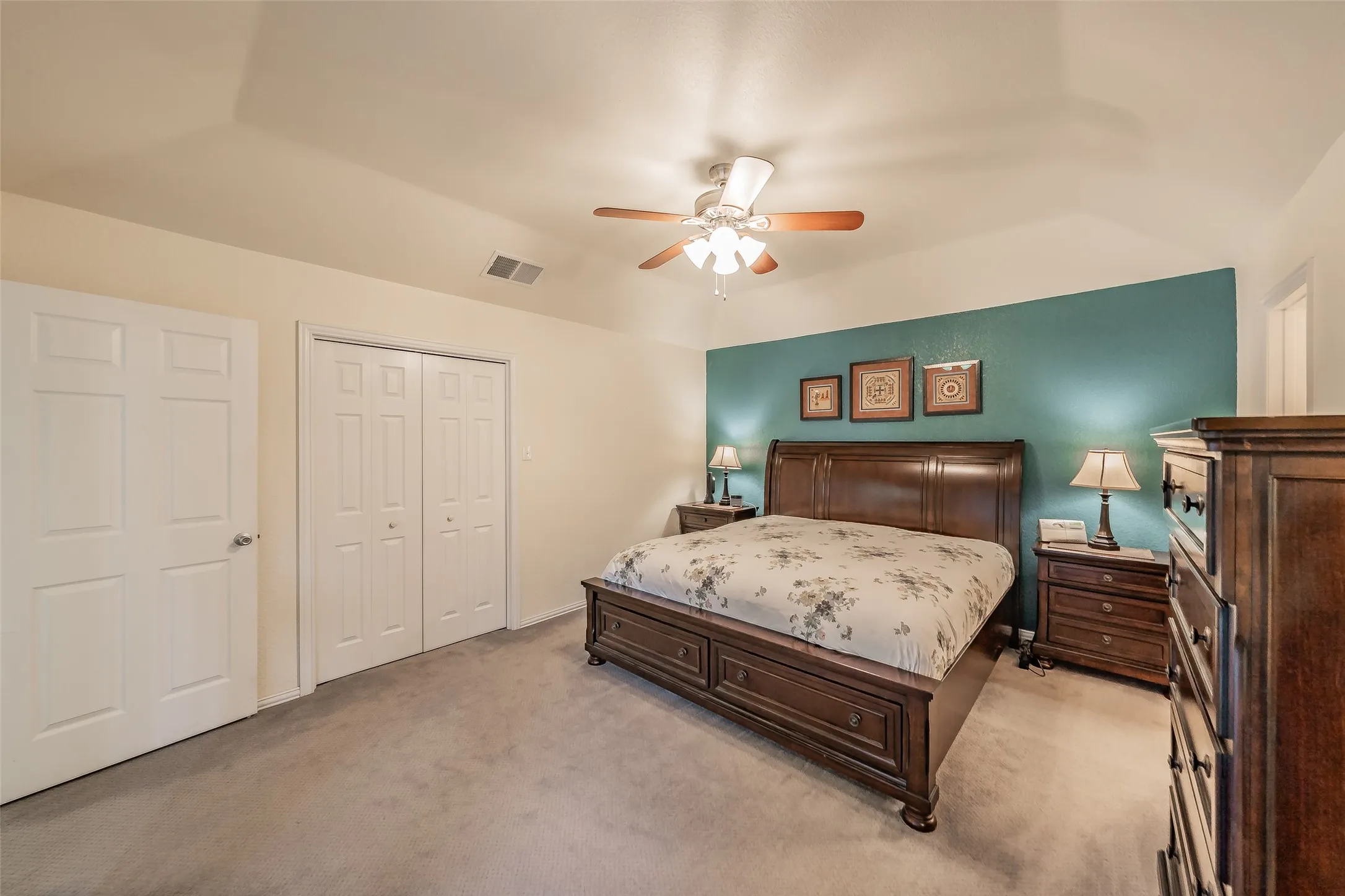 Vaulted ceiling, ceiling fan, teal accent wall, carpet flooring, and white panel doors.  Third closet in the bedroom.  There are 2 more in the primary bathroom.