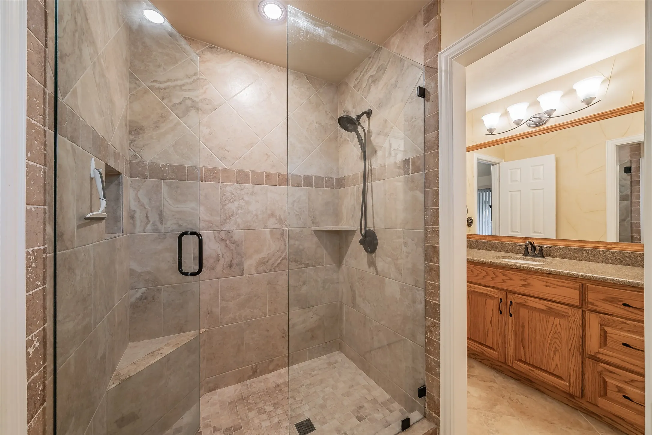 Walk-in shower with full-height tile surround, built-in bench, and glass enclosure