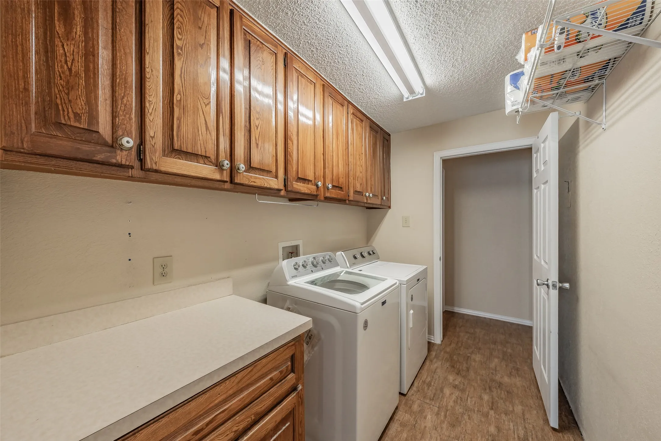 Wood-finish upper cabinetry, light-toned countertop, and tile flooring