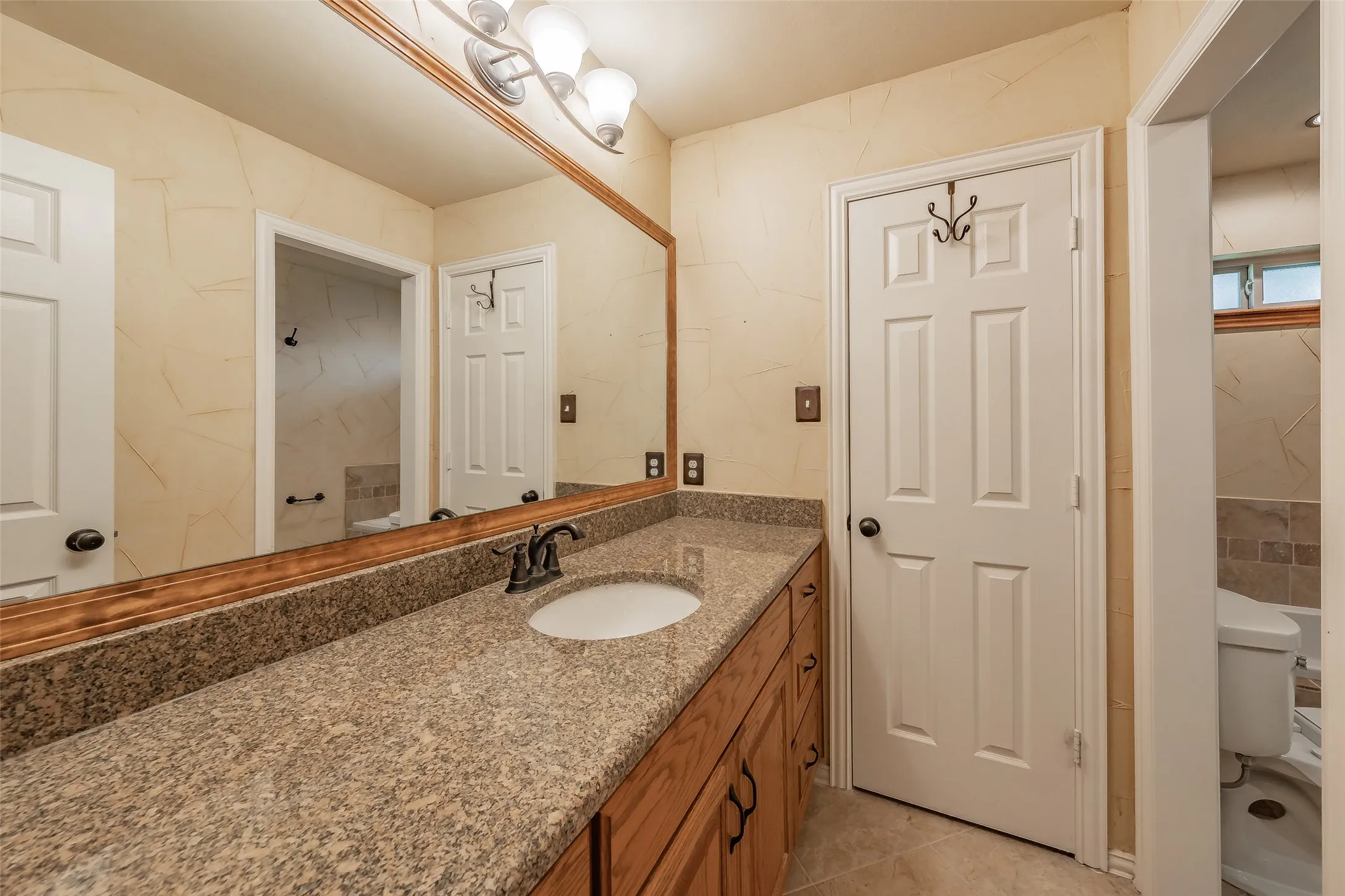 Extended vanity with integrated sink, bronze-finish faucet, and substantial mirror