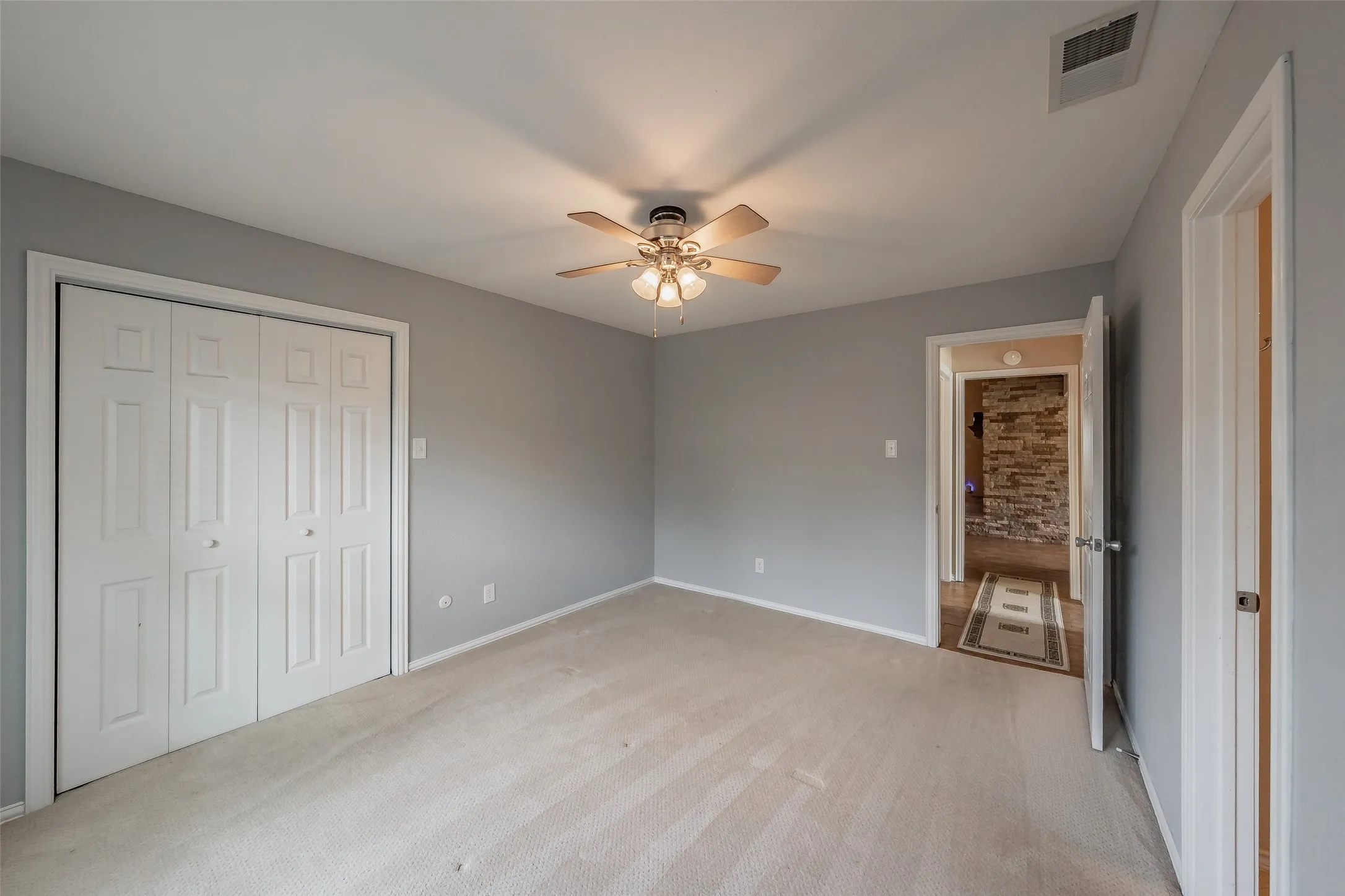Carpeted room featuring a ceiling fan with integrated lighting, bi-fold closet doors, and neutral wall paint
