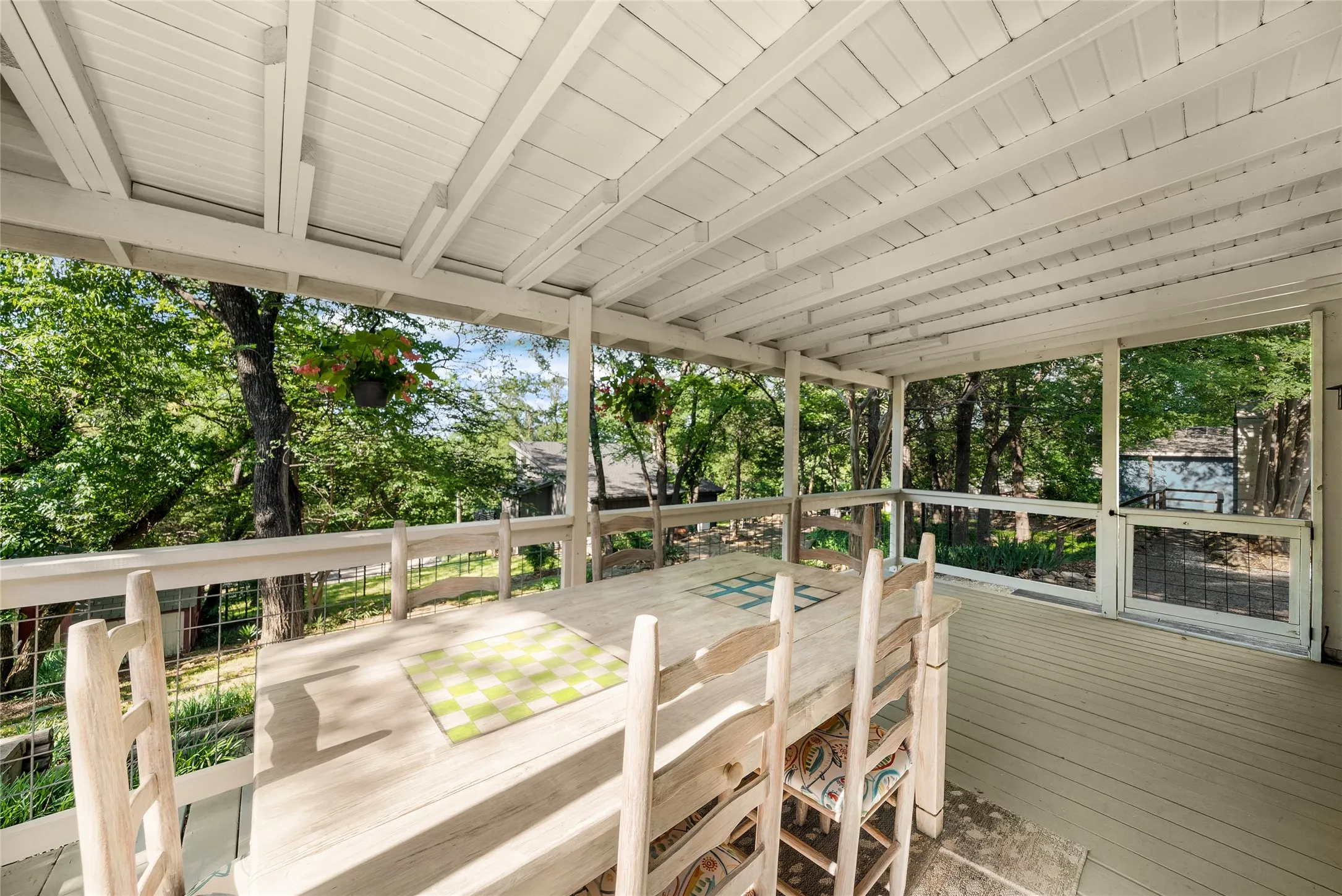 Covered porch with exposed beam ceiling, painted wood flooring, and screened enclosure