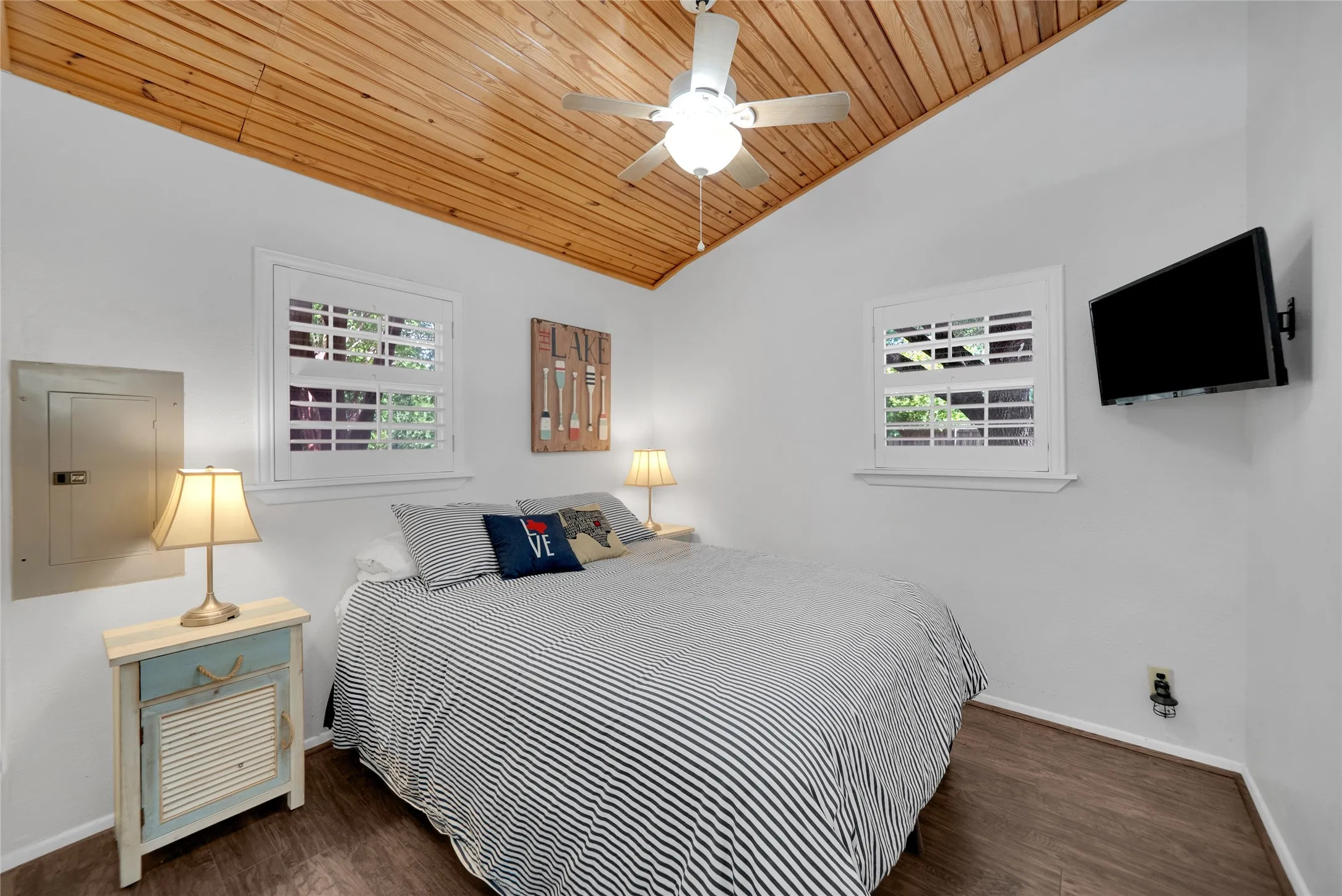 Vaulted wood-paneled ceiling, white walls, wood-finish flooring, and white plantation shutters