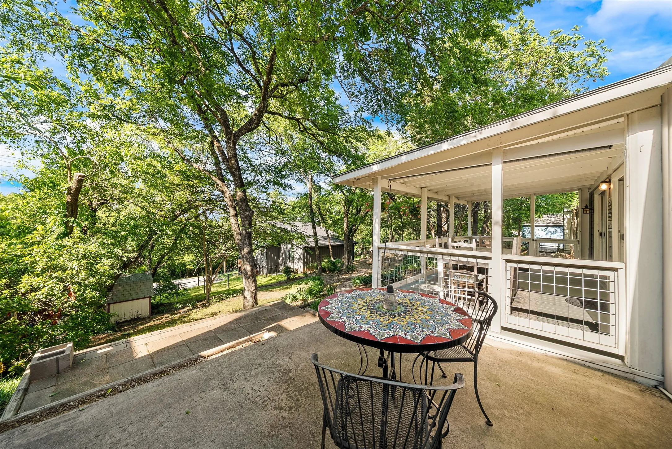 Covered patio with a concrete floor, glass railing, and white columns