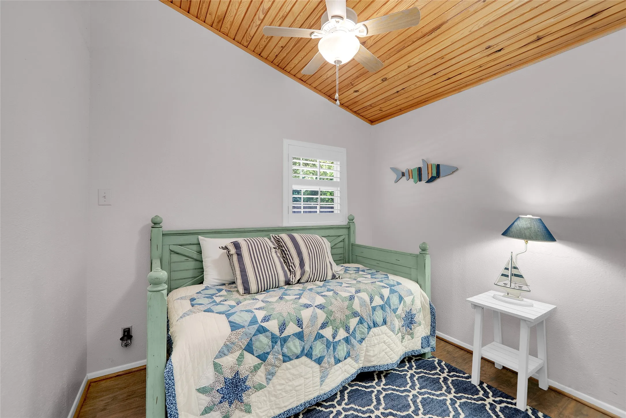 Vaulted wood-finish ceiling with a ceiling fan, wood-finish flooring, and a window with plantation shutters