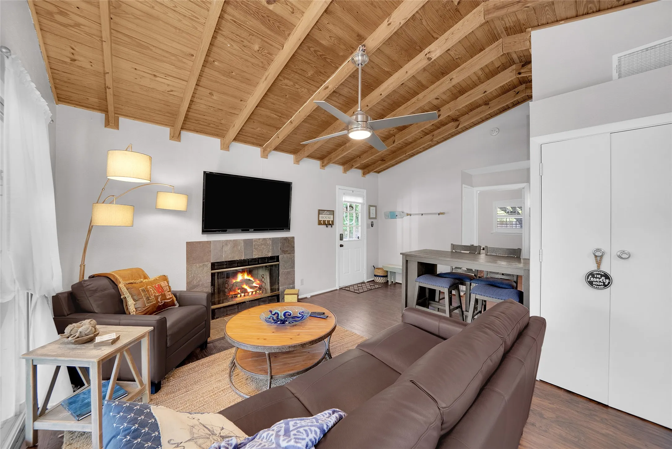 Vaulted wood-plank ceiling, ceiling fan, fireplace with stone surround, wood-finish flooring, and white bi-fold closet doors