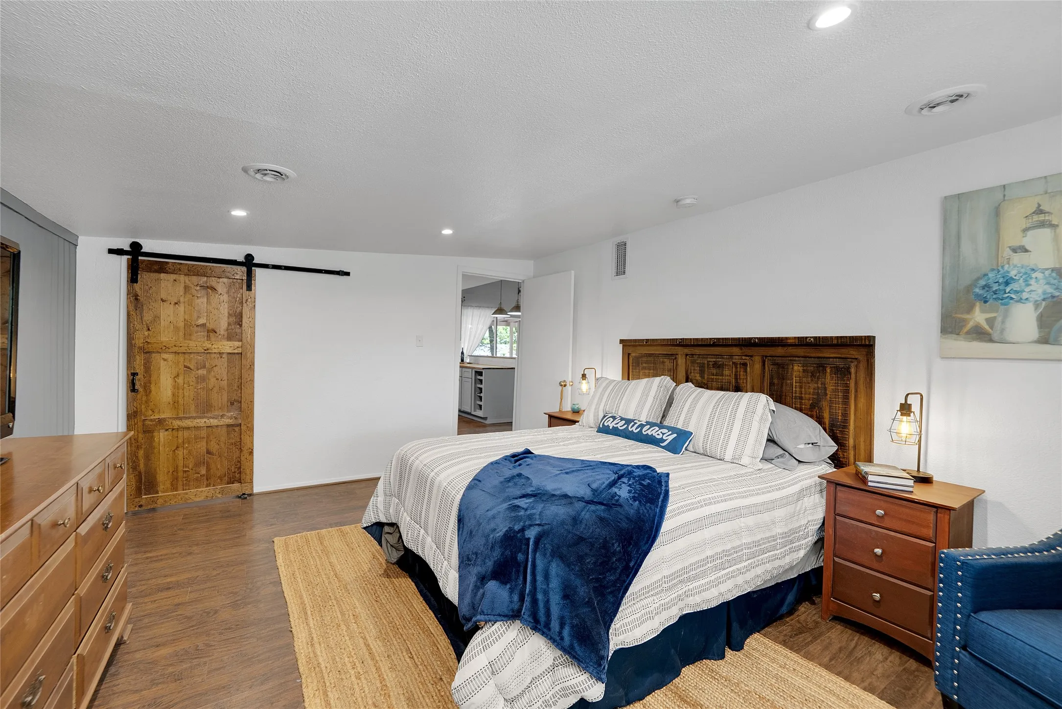 Wood-finish flooring throughout, recessed lighting, and a wood barn door