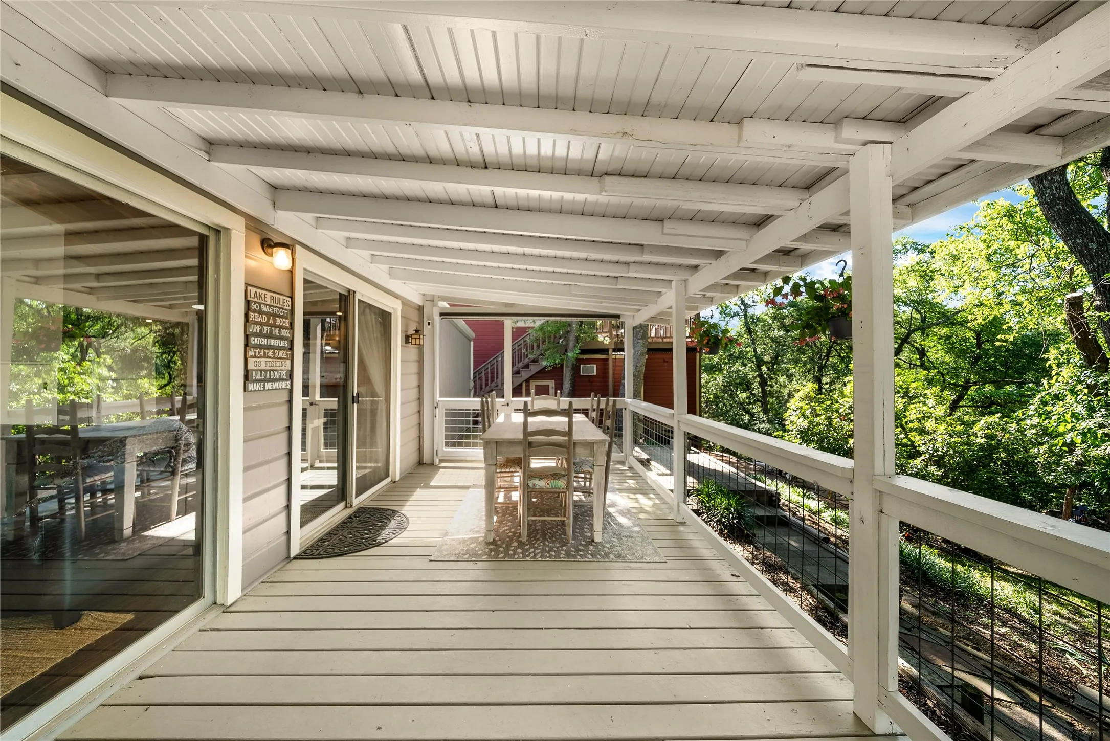 Expansive covered deck with light-toned decking, white painted wood railings, and multiple sliding glass doors