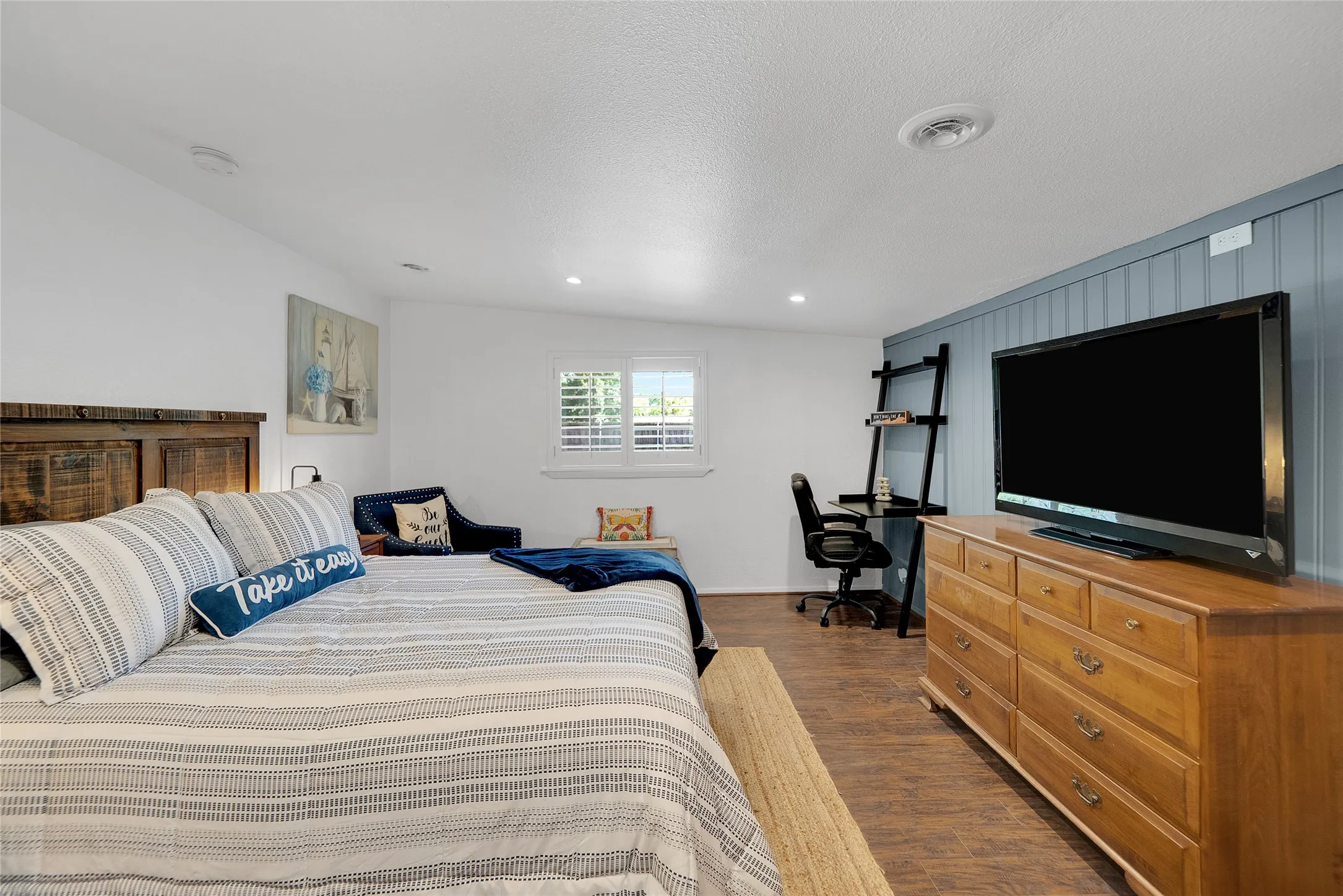 Wood-finish flooring, recessed lighting, and a white shuttered window