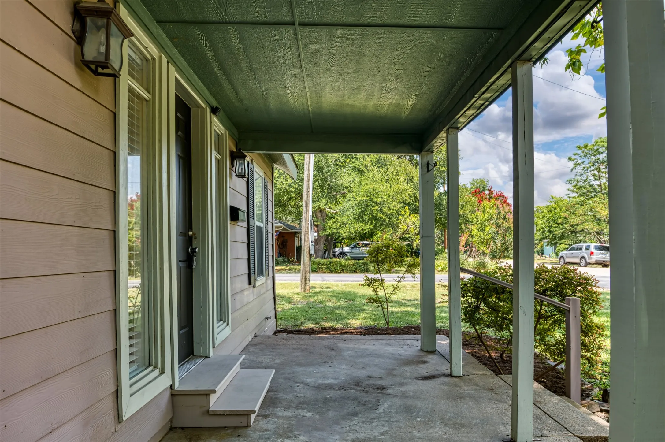 Covered front porch with concrete flooring and wood support pillars