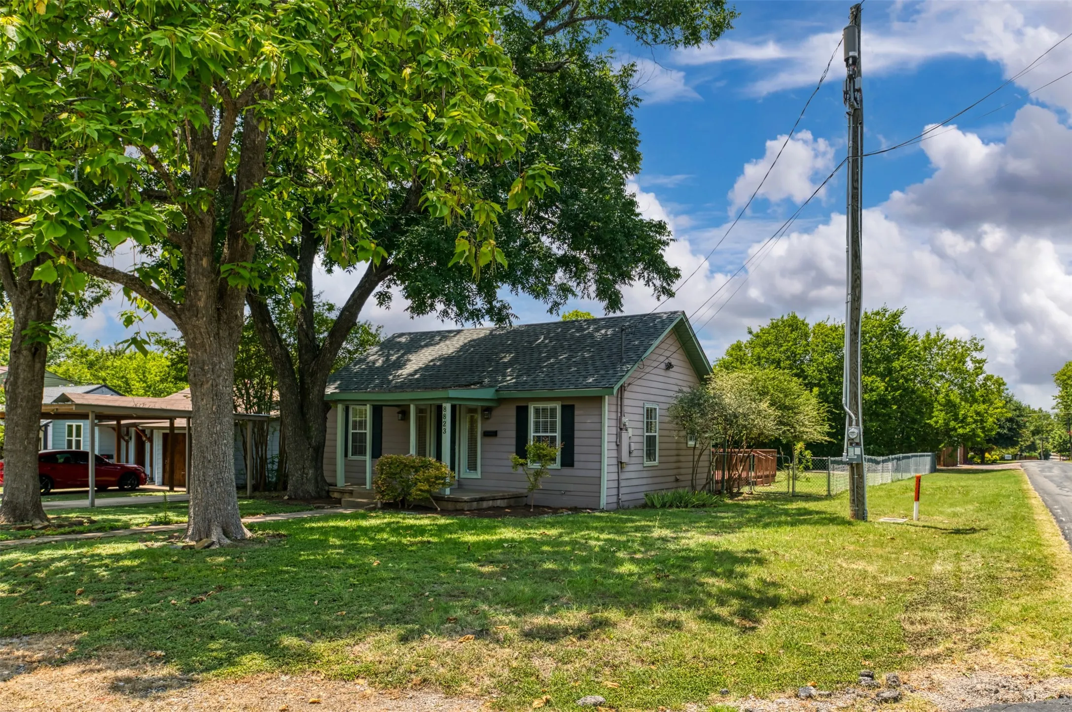 Single-story residence featuring light-colored siding, a covered front porch, and a dark-shingled roof