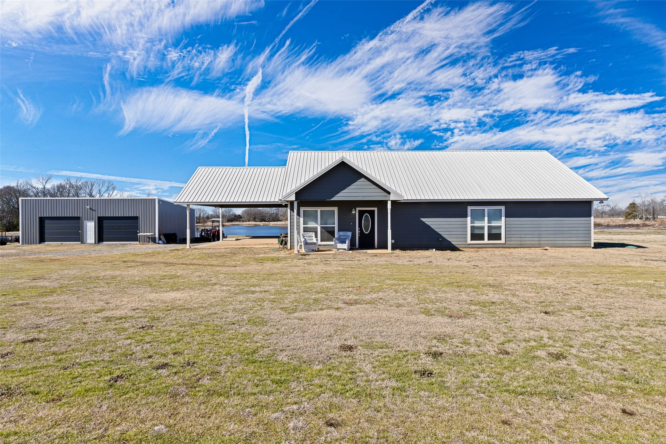 View of front of home with an outbuilding, a carport, a garage, and a front lawn