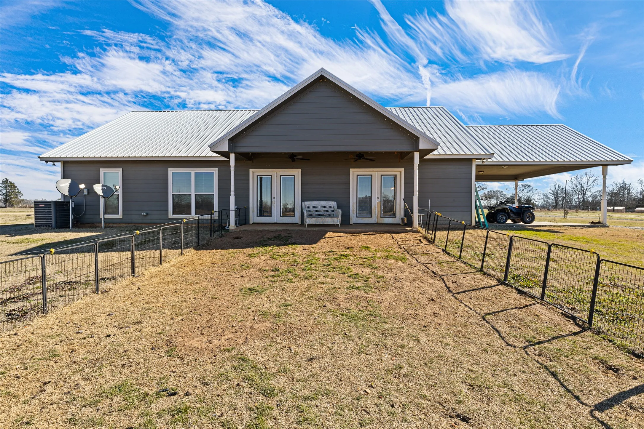 View of front of property featuring a front lawn, ceiling fan, and french doors