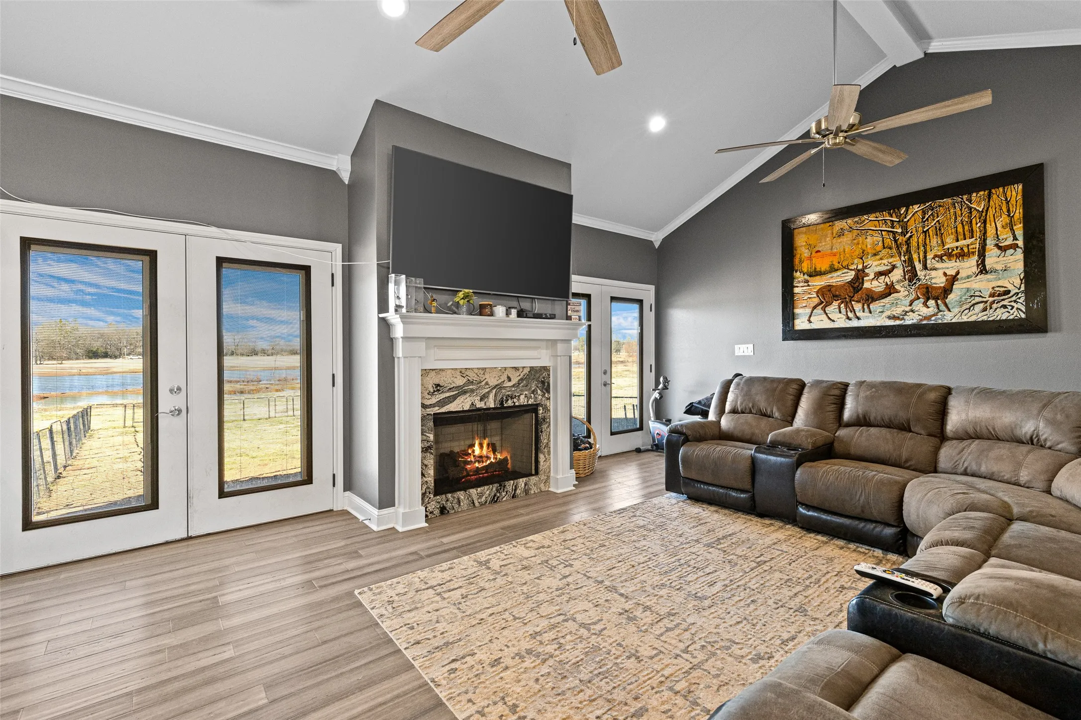 Living room with crown molding, a premium fireplace, lofted ceiling with beams, and french doors