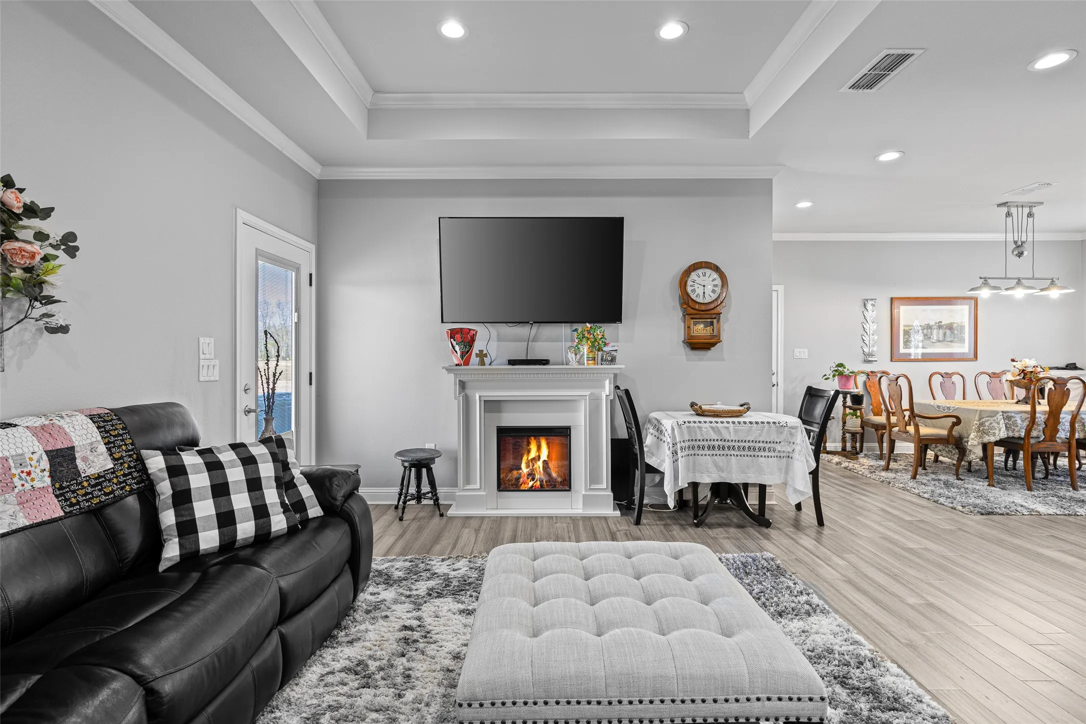 Living room with a raised ceiling, crown molding, and hardwood / wood-style floors