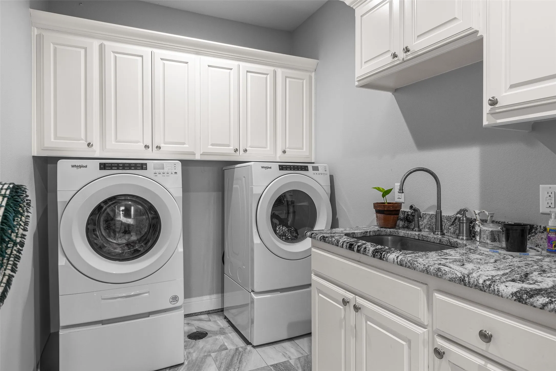 Clothes washing area with cabinets, separate washer and dryer, and sink