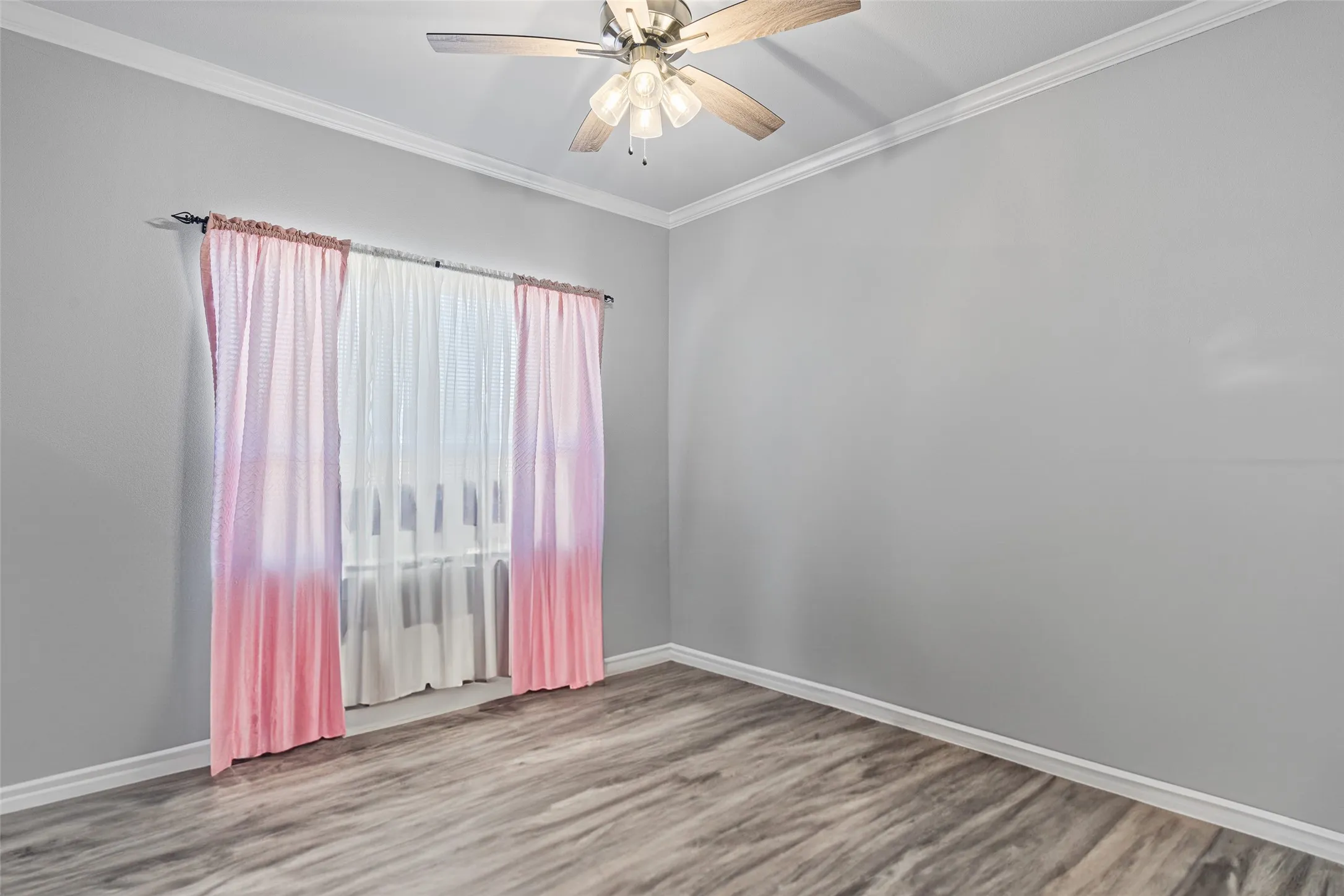 Spare room featuring wood-type flooring, ornamental molding, and ceiling fan