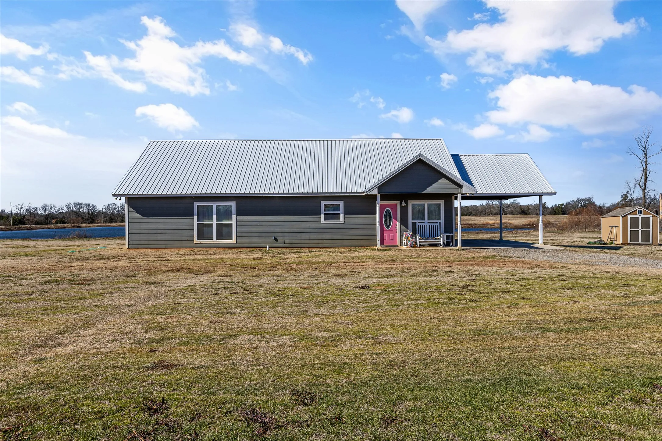 View of front of house featuring a carport, a storage unit, and a front yard