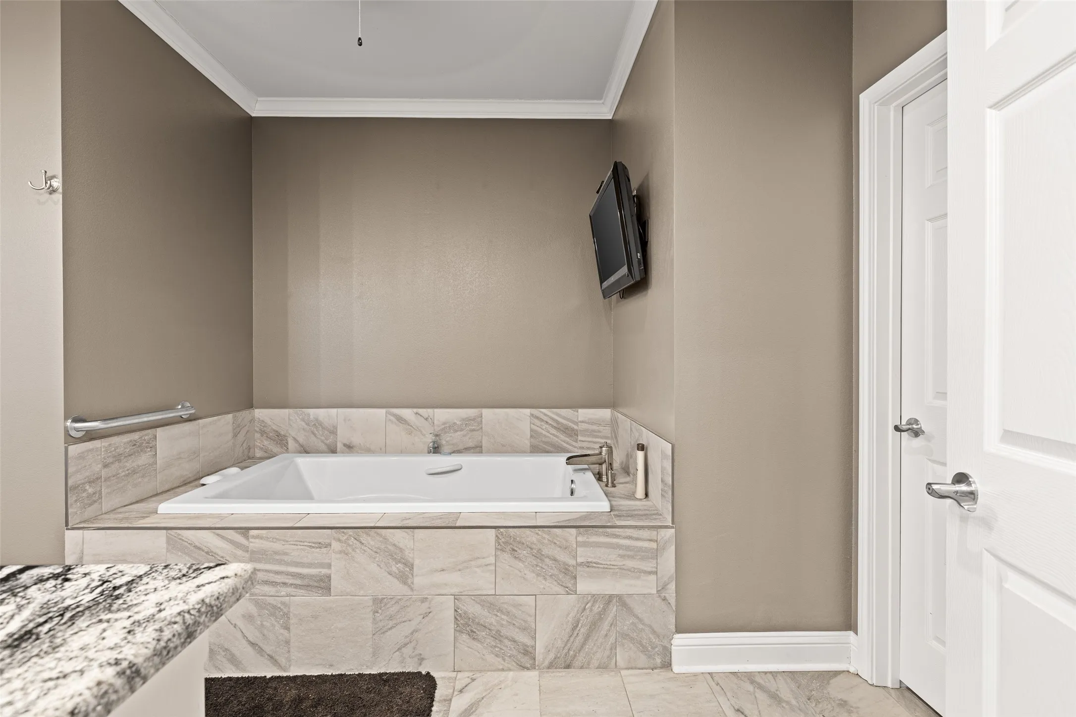 Bathroom with a relaxing tiled tub and ornamental molding