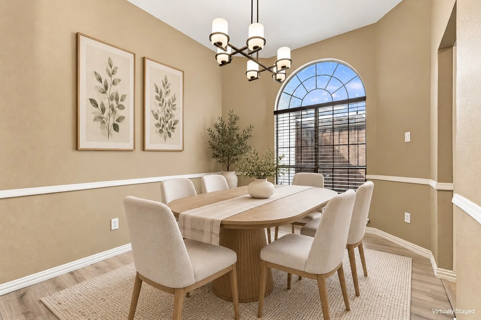 Arch-top window with grid pattern, overhead chandelier, decorative wall molding, and wood-finish flooring