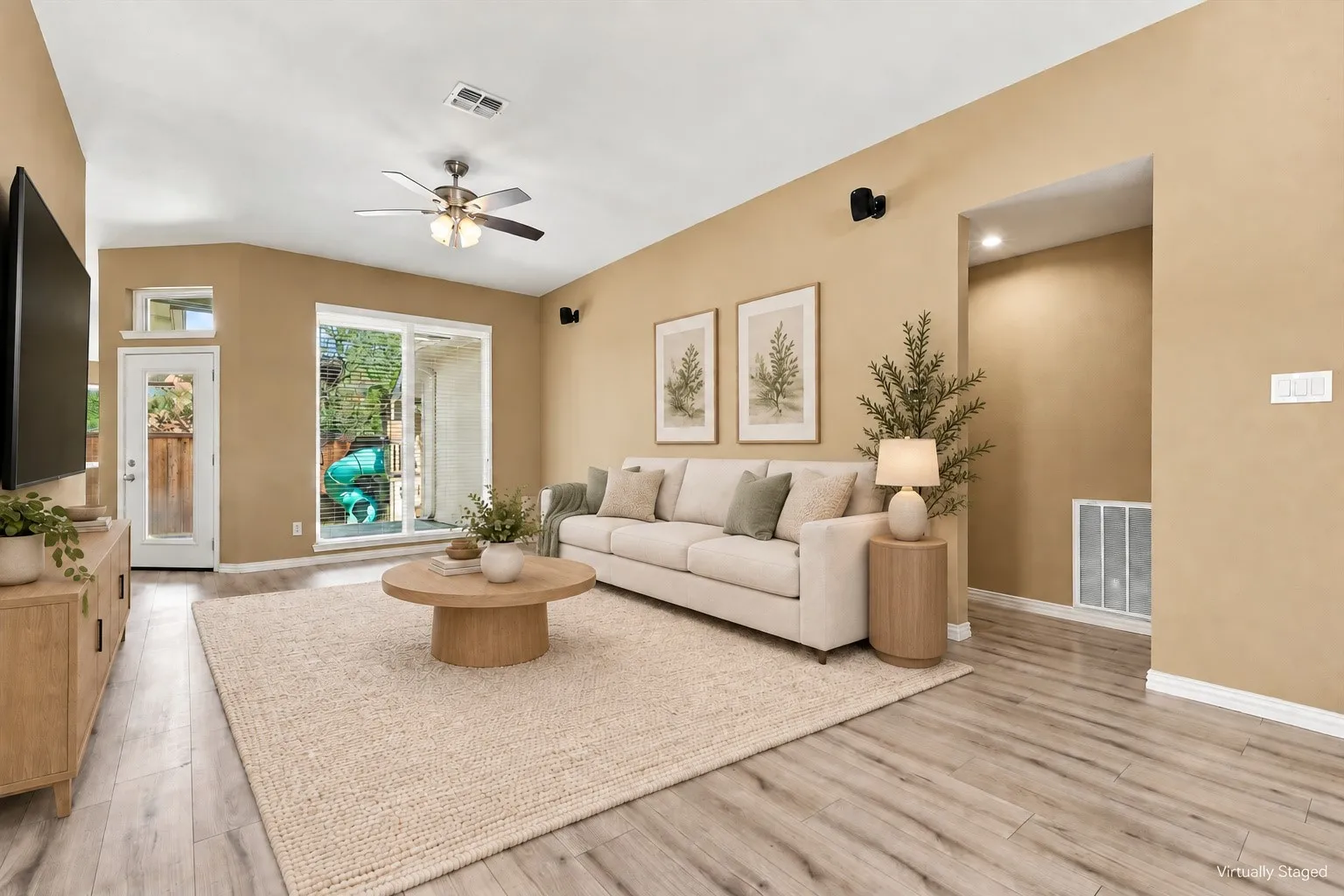 Wood-finish flooring, vaulted ceiling, ceiling fan, recessed niche with lighting, and a sliding glass door with transom window