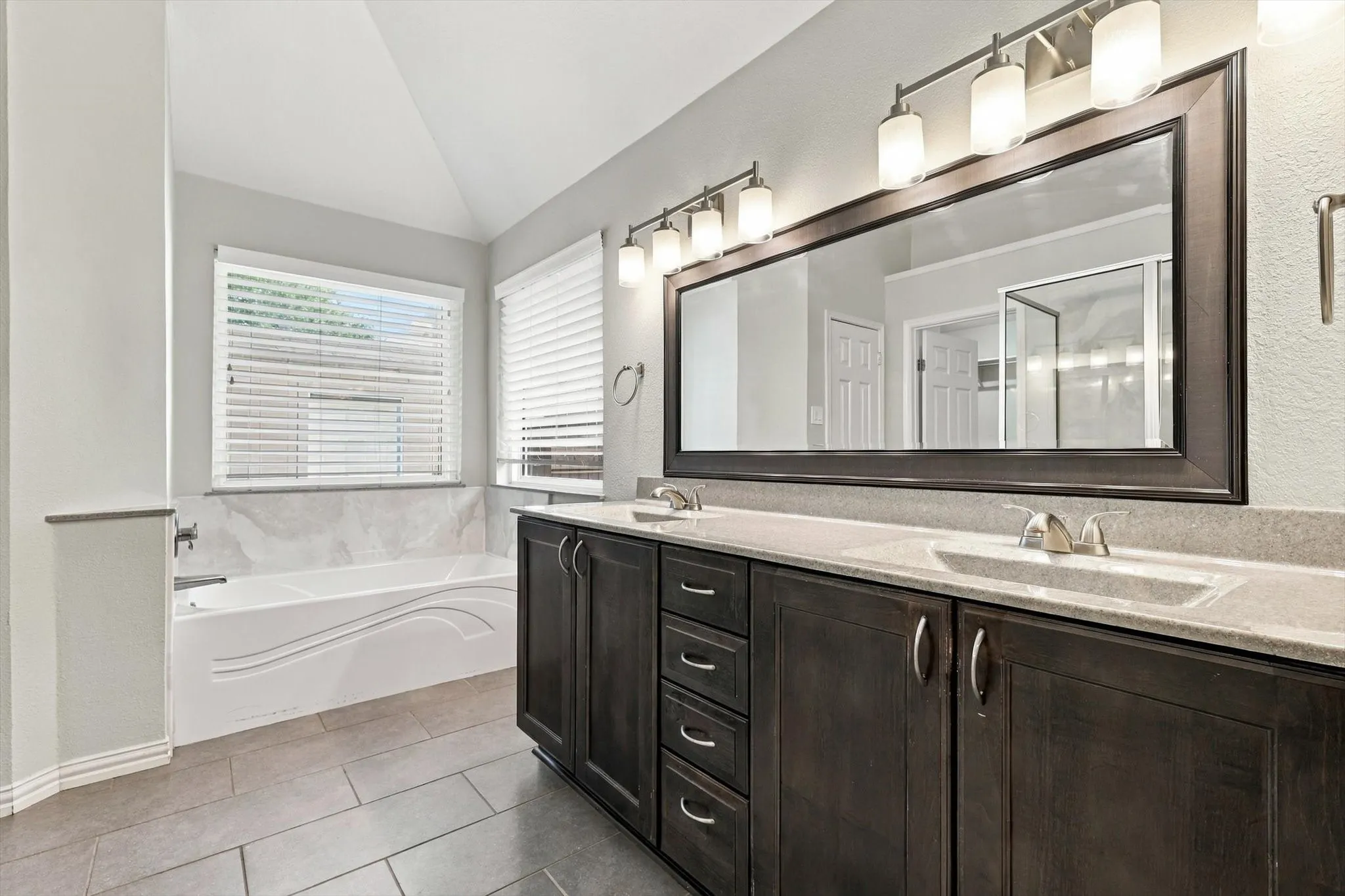 Dual vanity with dark wood-finish cabinetry, integrated sinks, and polished chrome fixtures