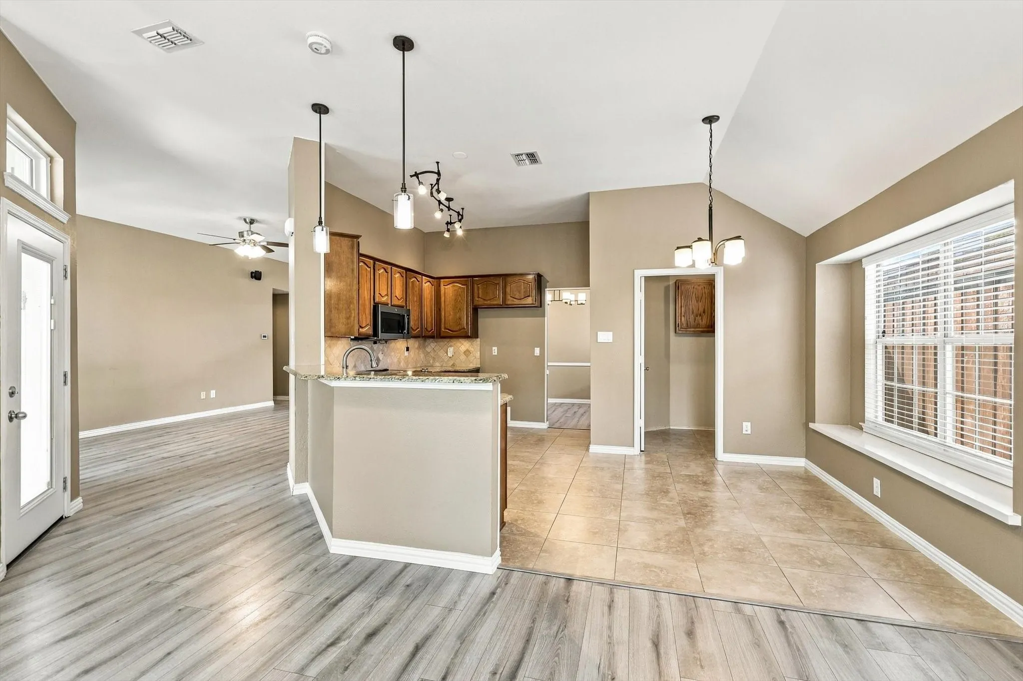 Vaulted ceilings with recessed lighting, wood-finish flooring, and a kitchen featuring wood cabinetry, an undermount sink, and a built-in microwave