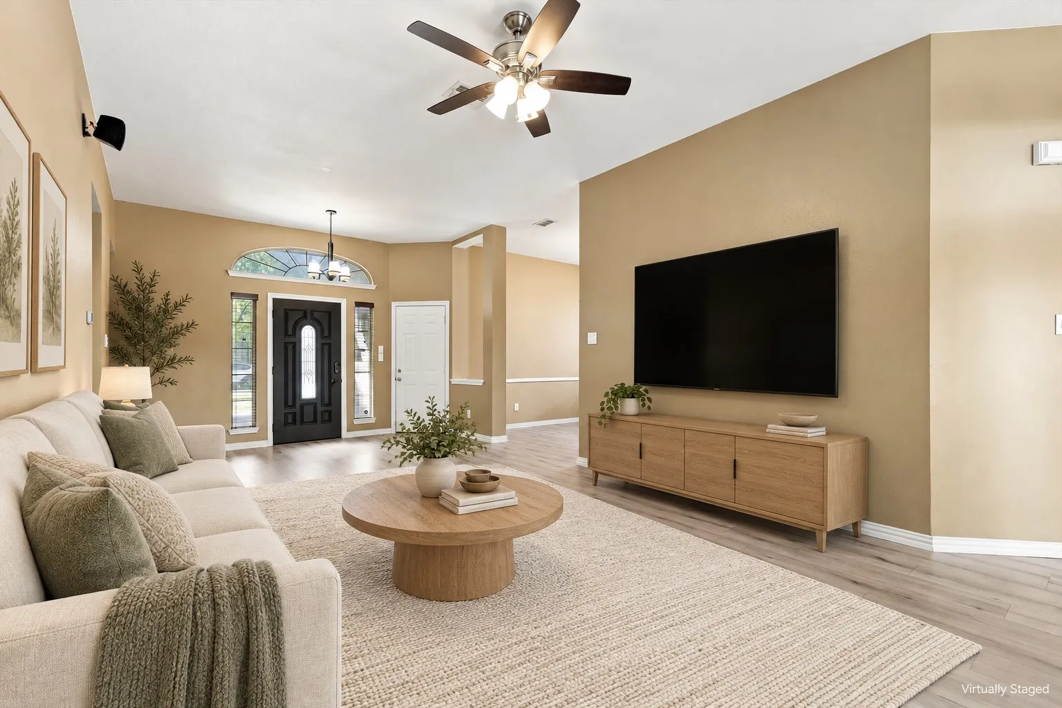 Vaulted ceiling with a ceiling fan, light wood-finish flooring, and a decorative front entry door with an arched transom window