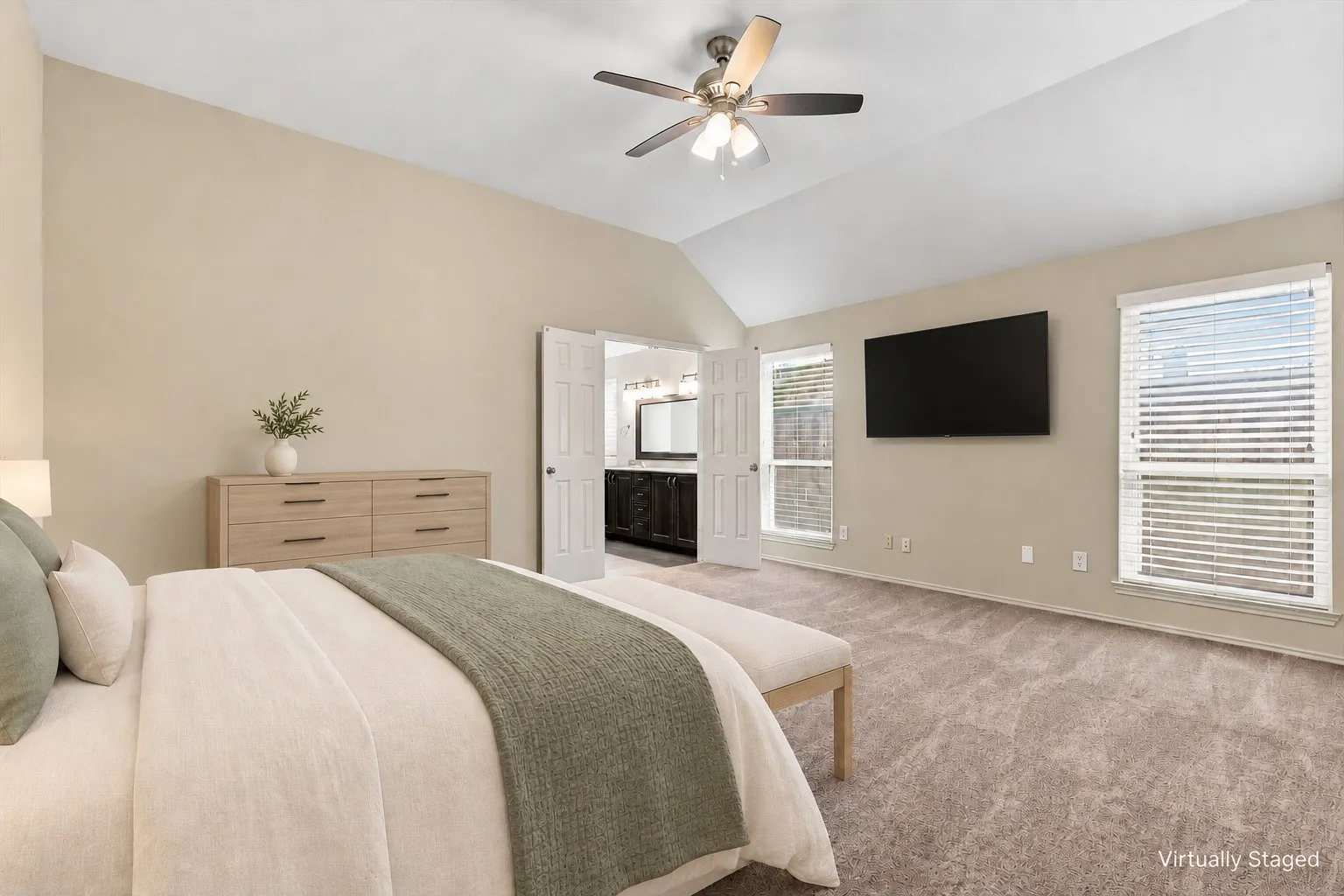 Vaulted ceiling, ceiling fan, two windows with blinds, carpet flooring, and double-door entry