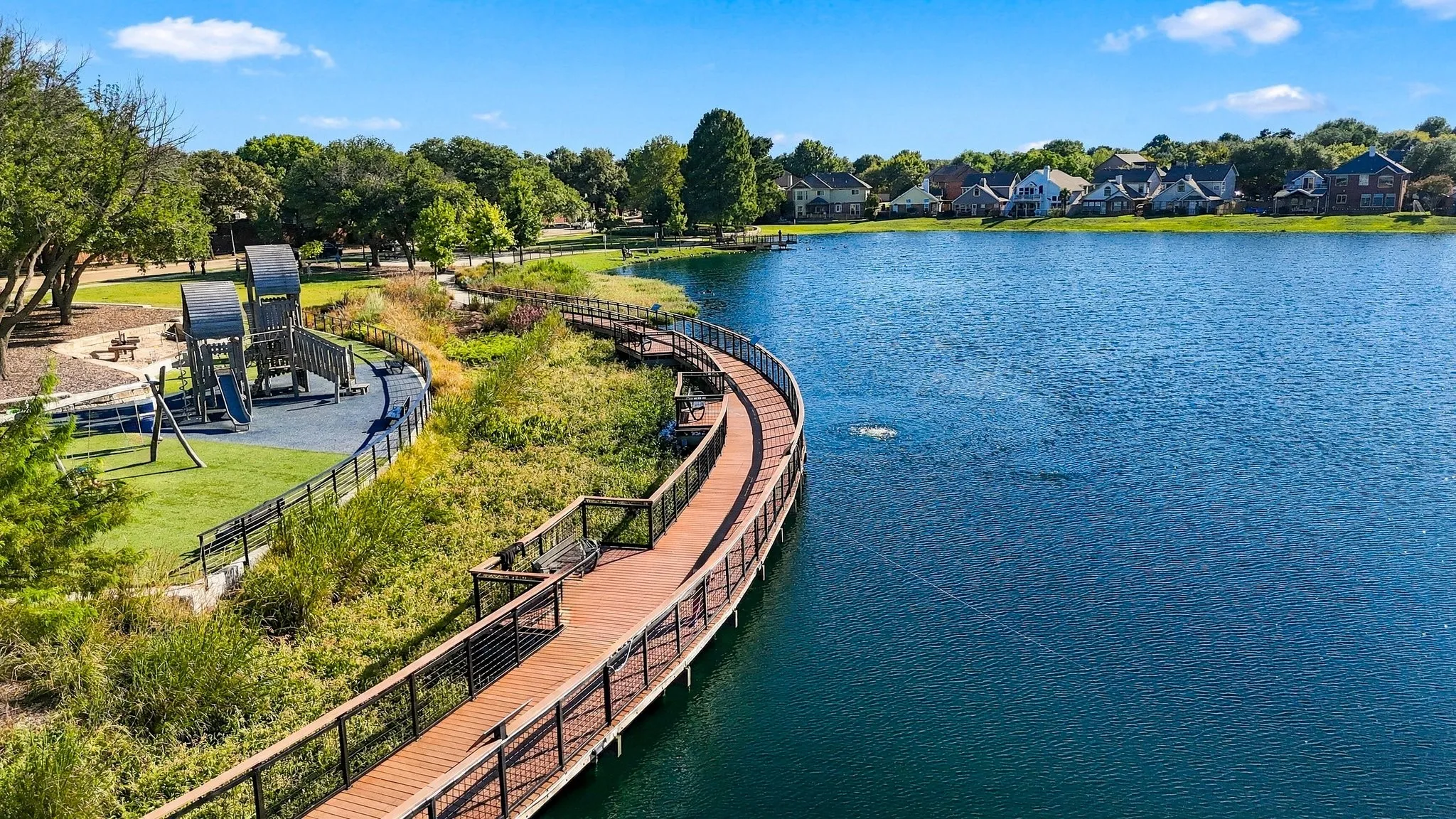Expansive waterfront property featuring a curved boardwalk, an integrated playground area, and a large body of water