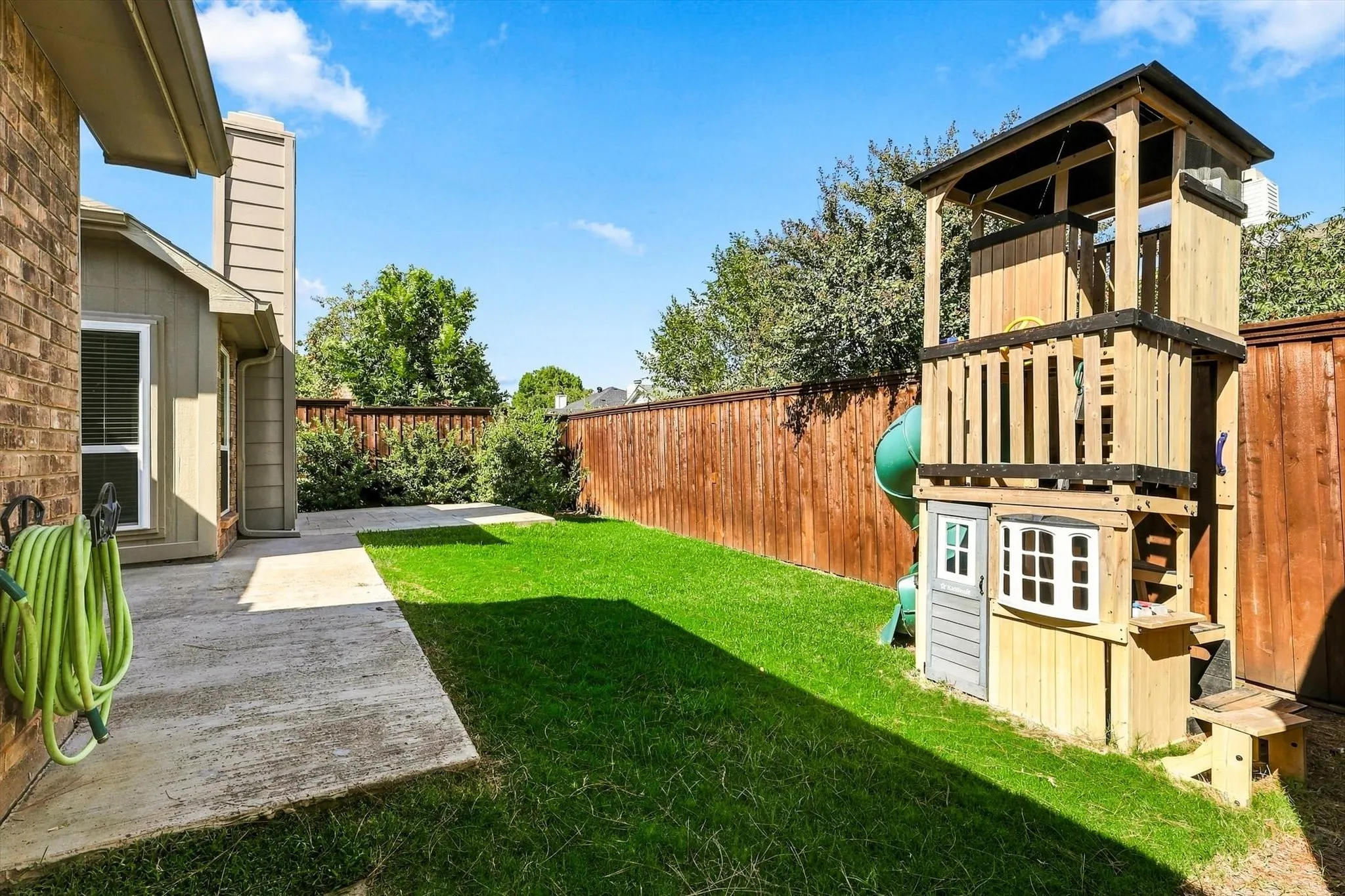 Expansive backyard featuring a manicured lawn, concrete patio, and privacy fencing