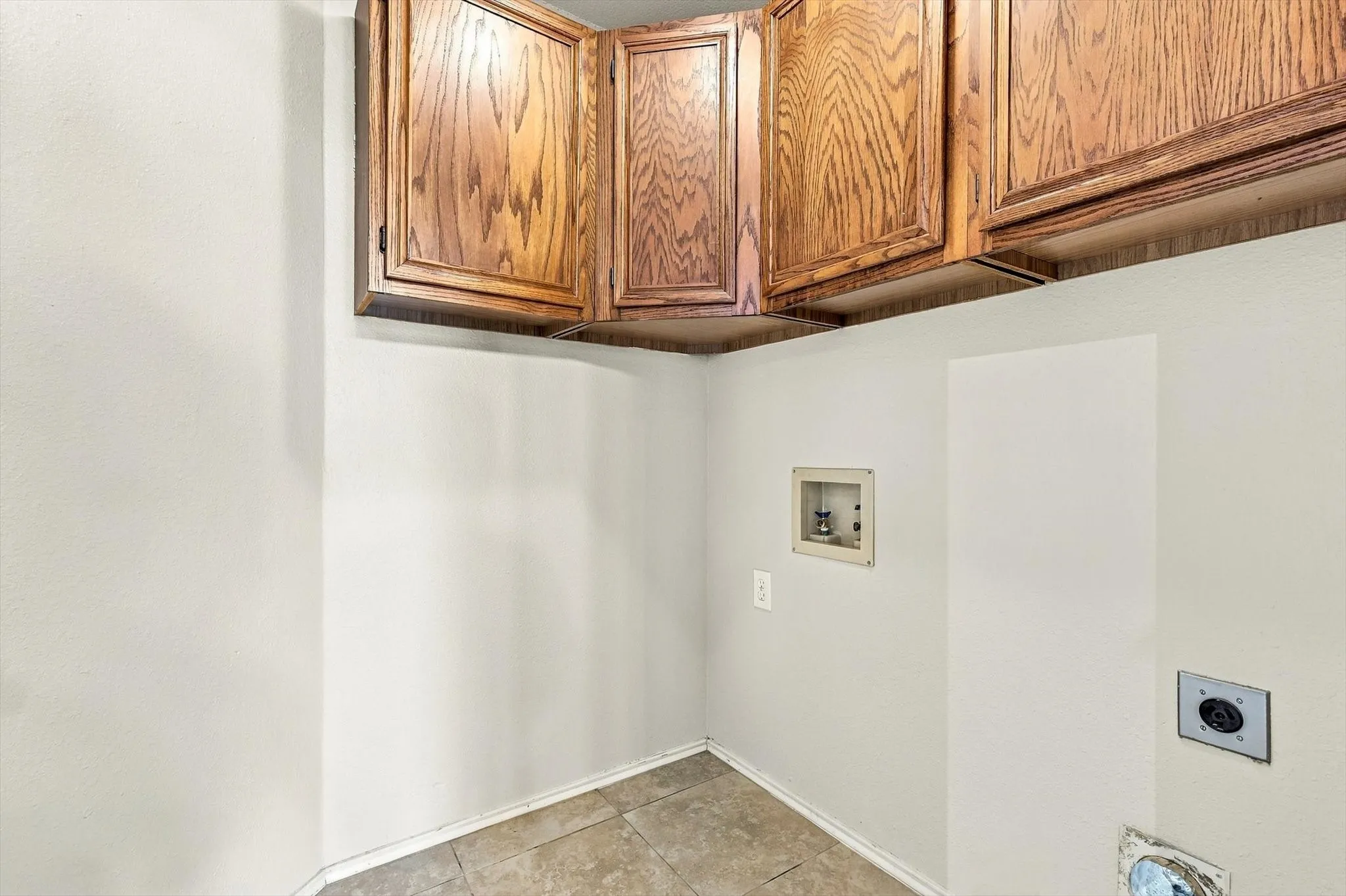 Upper wood-finish cabinetry, tile flooring, and light-toned walls