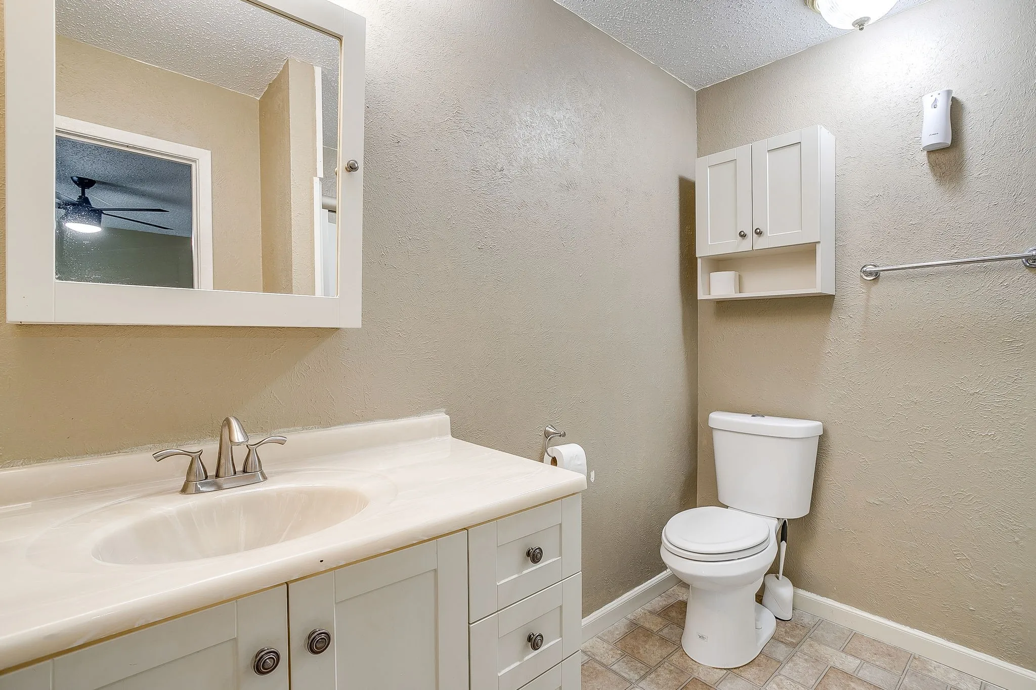 Bathroom featuring a vanity with an integrated sink and brushed nickel faucet, a wall-mounted medicine cabinet, and a white toilet