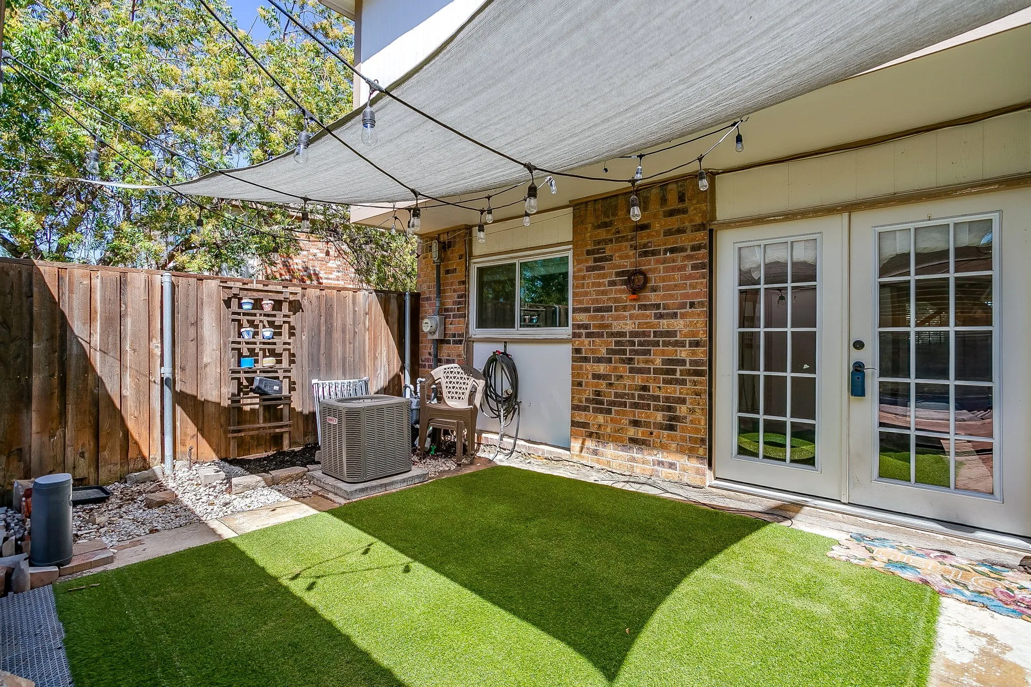 Brick exterior with French doors and an artificial turf patio
