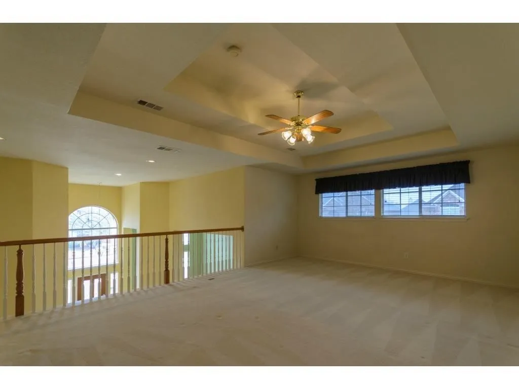Tray ceiling with a ceiling fan, recessed lighting, and carpeted flooring