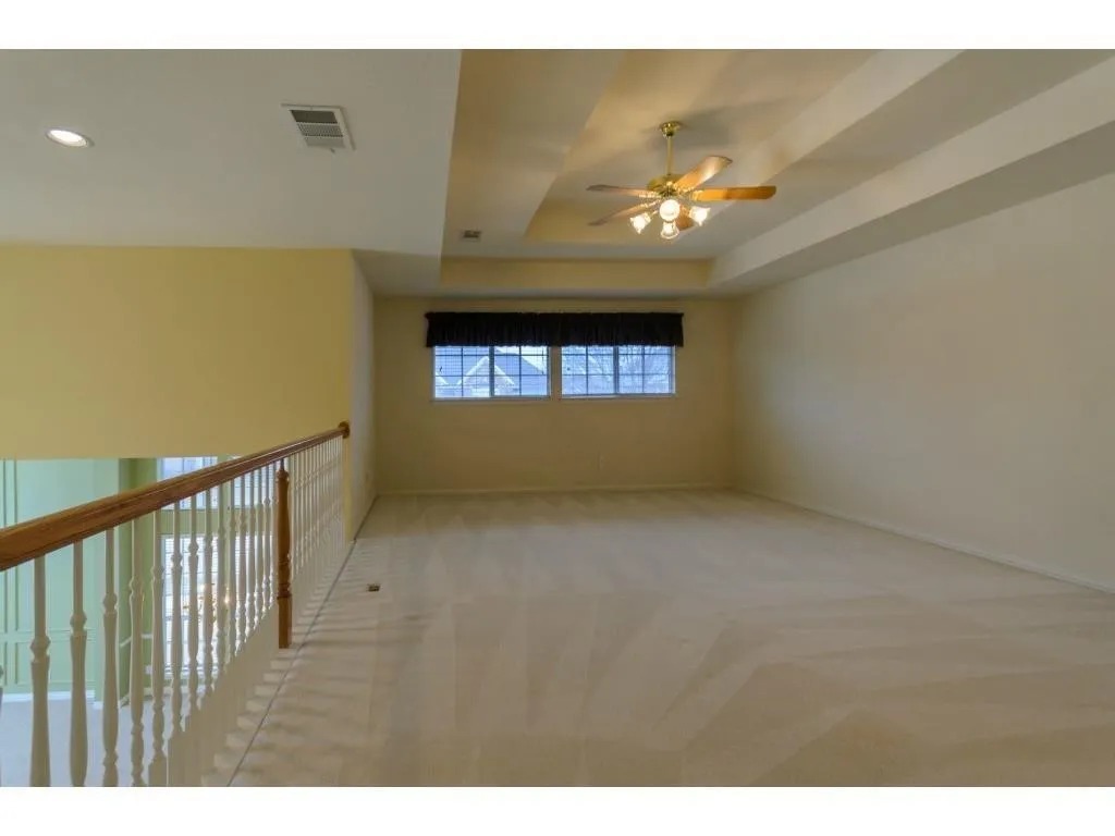 Tray ceiling with ceiling fan light fixture, recessed lighting, carpet flooring, and window with dark blinds