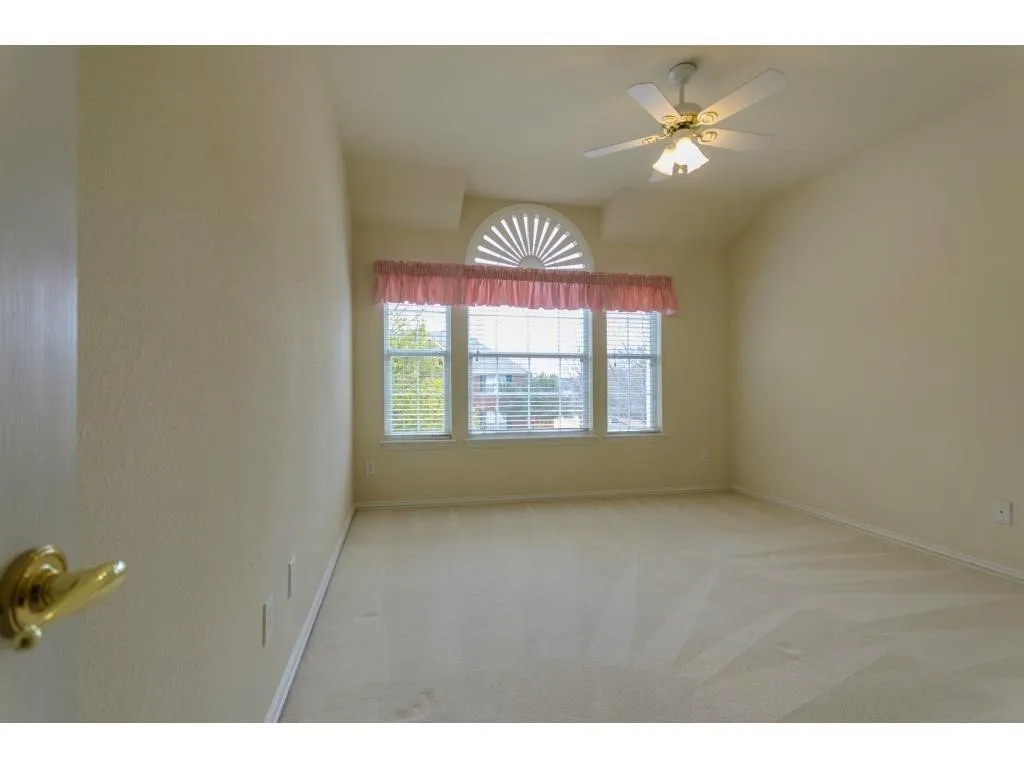 Vaulted ceiling with a ceiling fan, arched transom window, and carpeted flooring