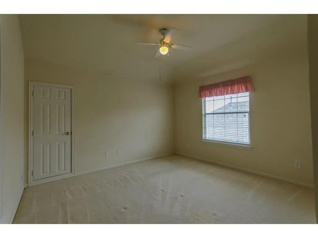 Vaulted ceiling, ceiling fan, neutral carpet flooring, white paneled door, and window with blinds