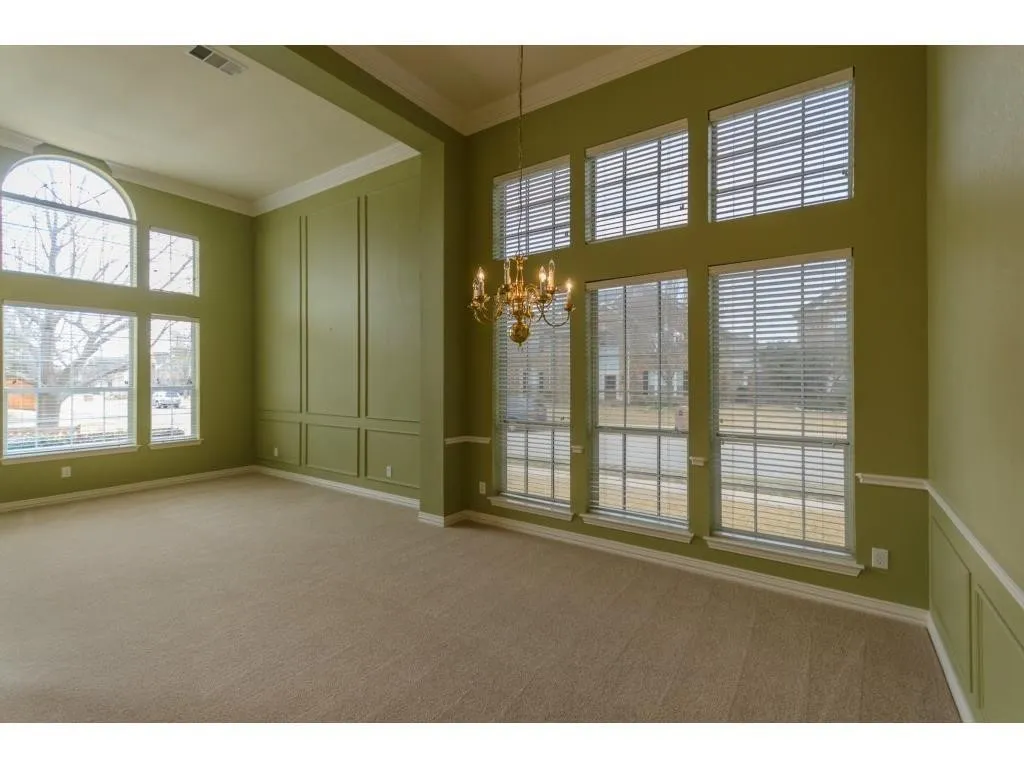 Expansive room featuring high ceilings, decorative wall paneling, and multiple windows including an arched transom window