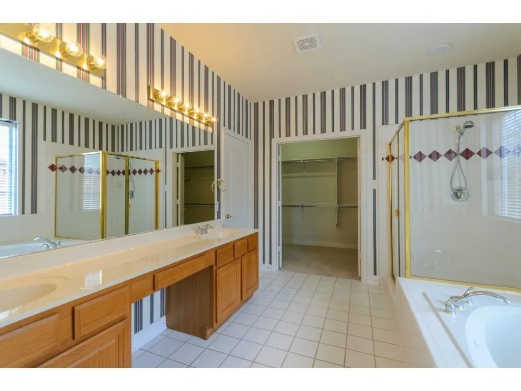 Dual vanity with integrated sinks, built-in cabinetry, and expansive mirror