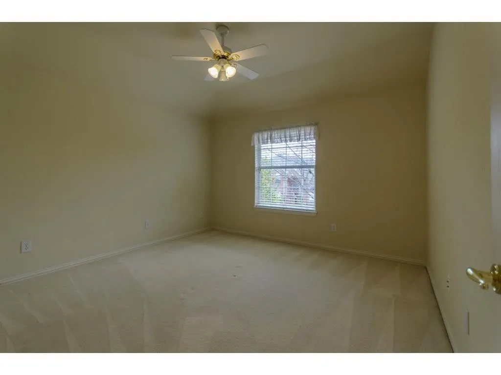 Vaulted ceiling with an attached ceiling fan, single window with blinds, and neutral carpeting