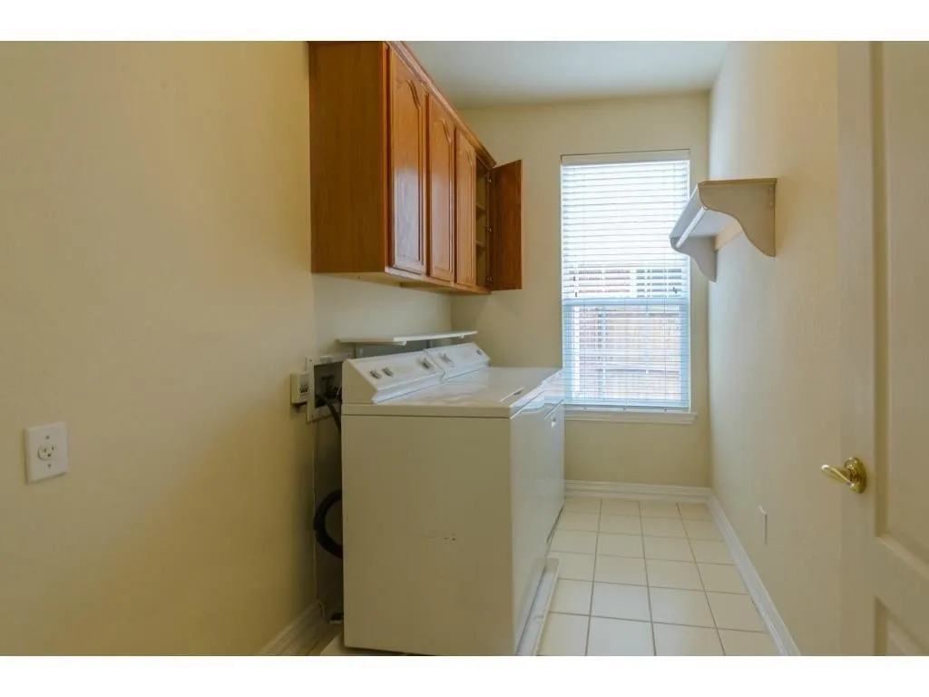 Tile flooring, wood-finish cabinetry, and a window with blinds